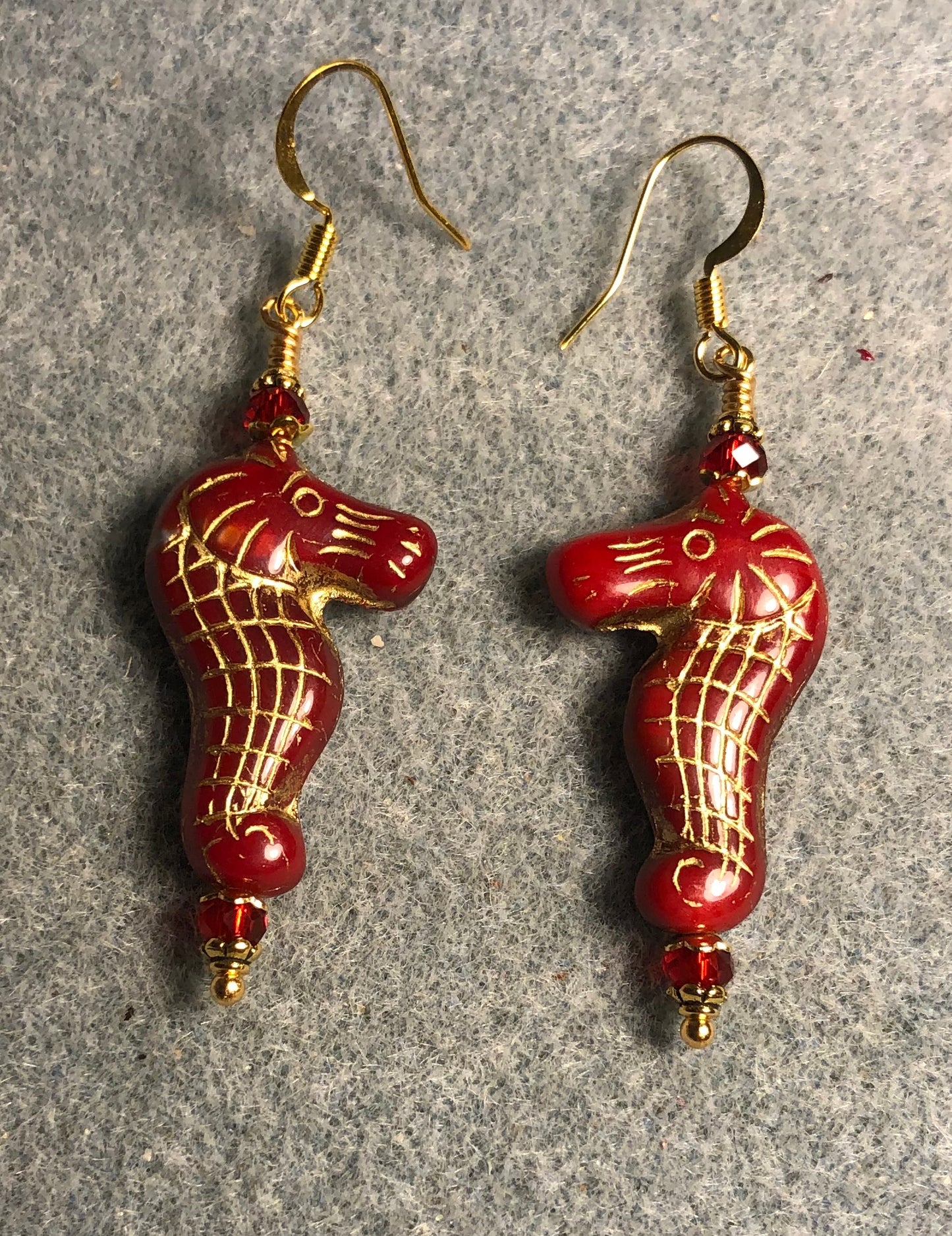 Dark red (with gold inlay) Czech glass seahorse bead earrings adorned with dark red Chinese crystal beads.