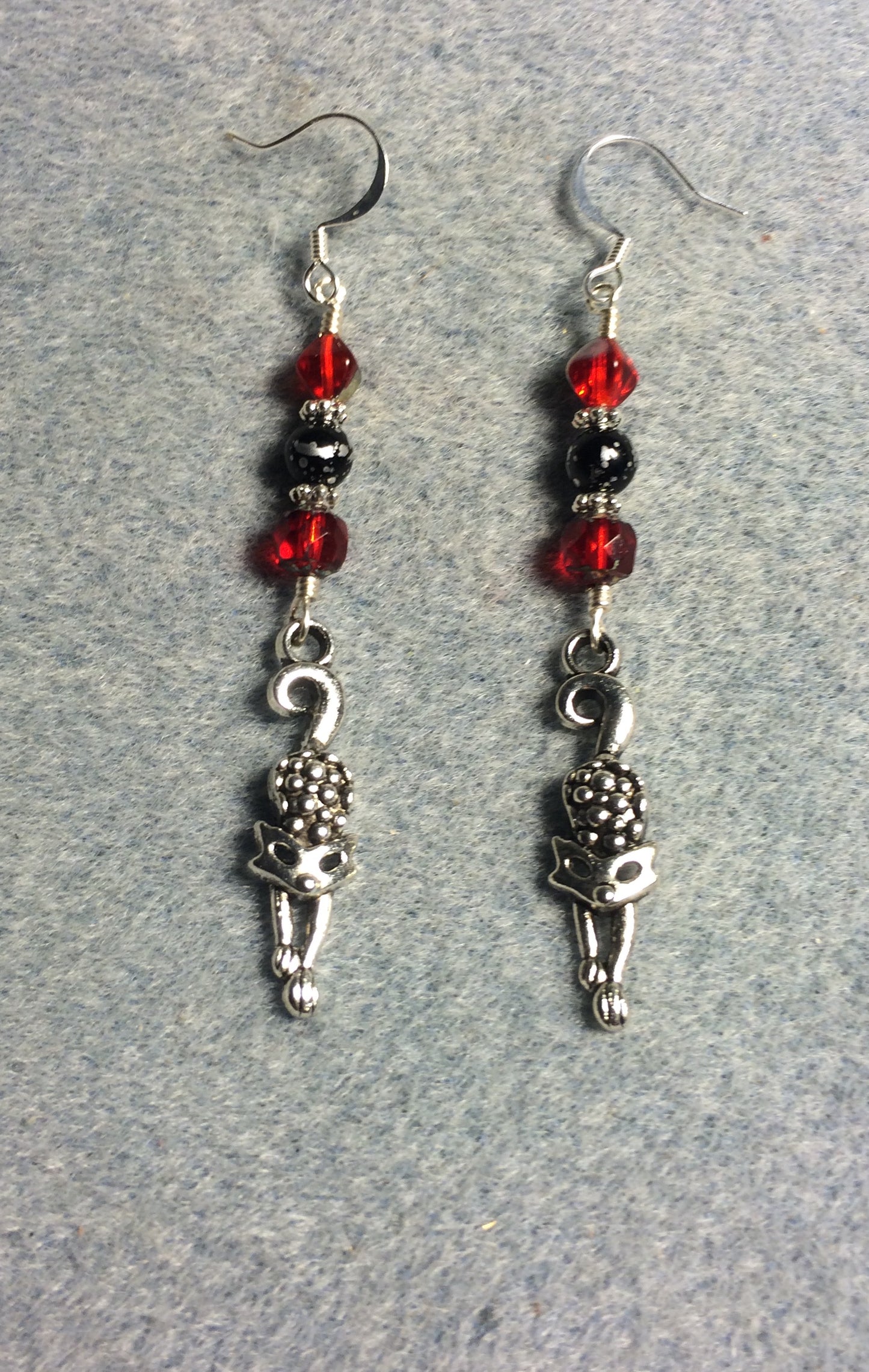 Silver stretching cat charm earrings adorned with red and black Czech glass melon beads.