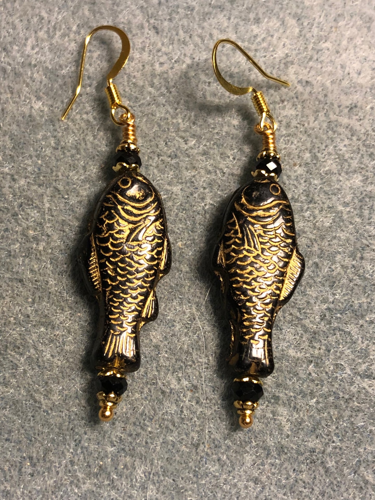 Black (with gold inlay) Czech glass fish bead earrings adorned with black Chinese crystal beads.