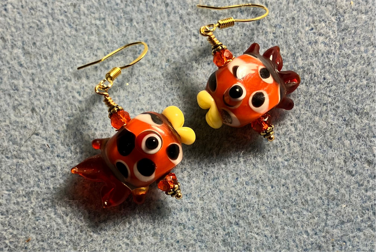 Orange and brown lamp work spotted fish bead earrings adorned with orange Chinese crystal beads.