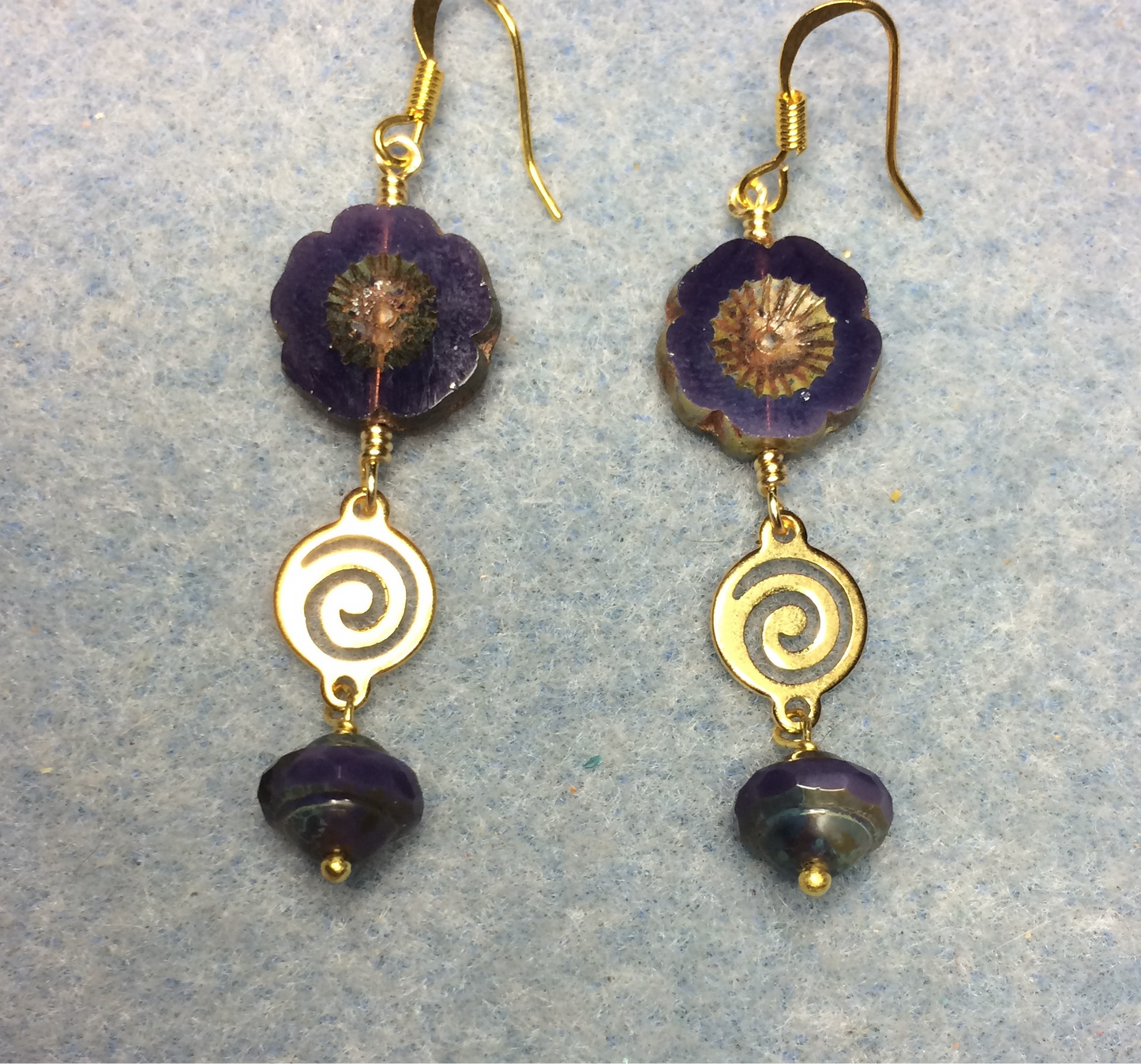 Opaque dark purple Czech glass pansy bead earrings adorned with gold swirly connectors and dark purple Czech glass Saturn beads.