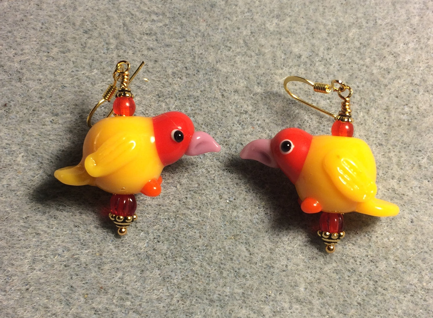 Yellow, red, and pink lamp work chicken bead earrings adorned with red Czech glass beads.