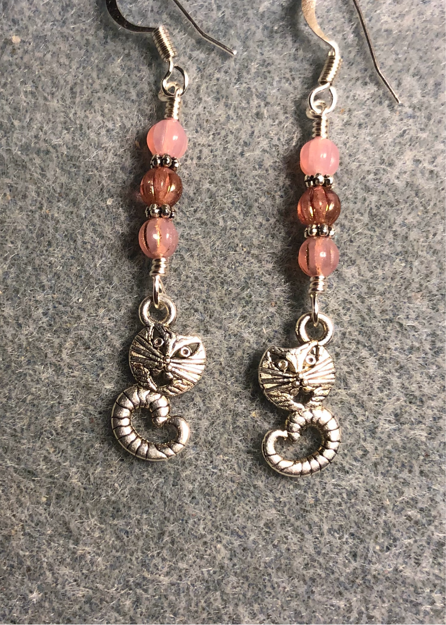 Silver Cheshire cat charm earrings adorned with milky pink Czech glass beads.