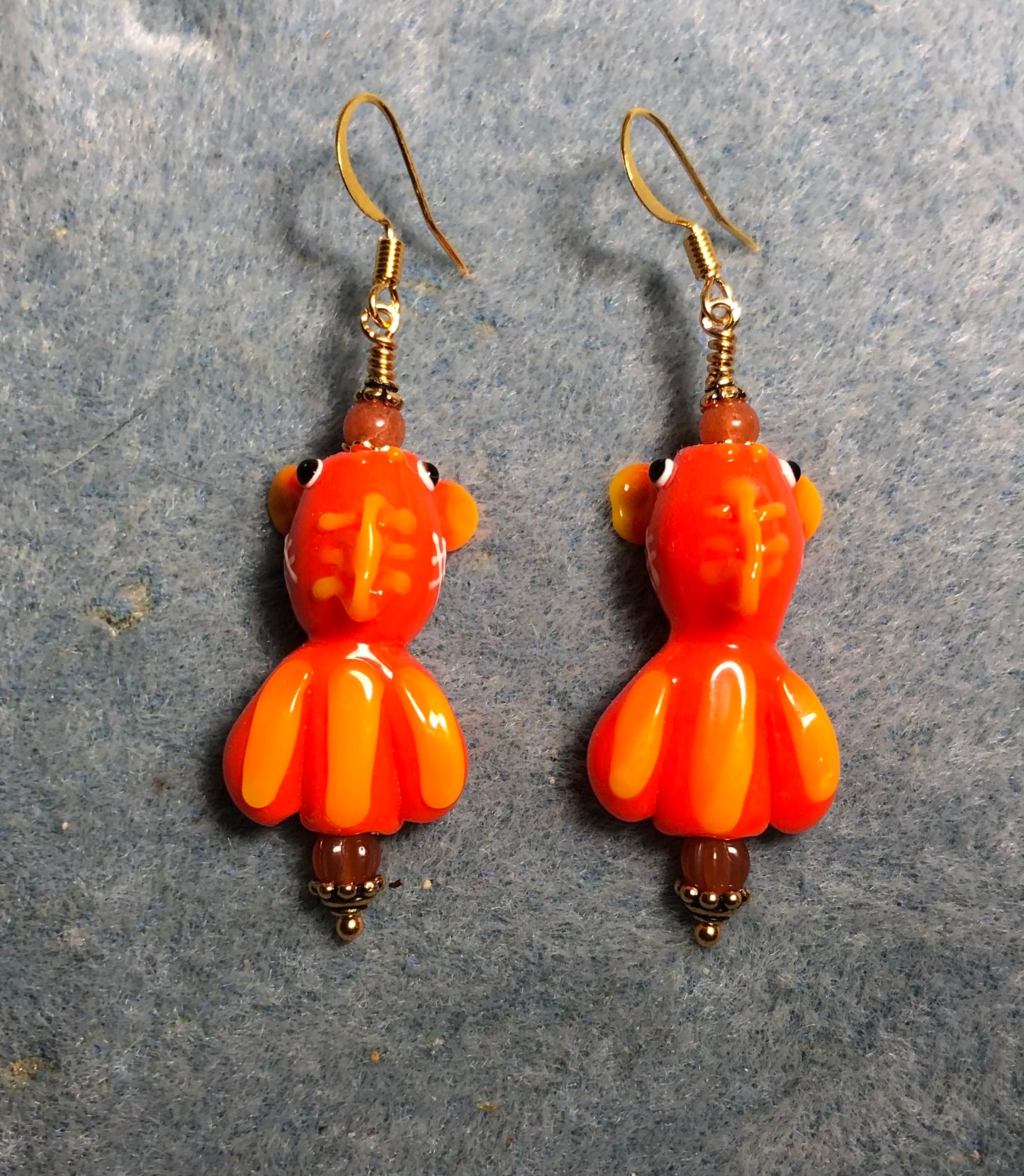 Orange and yellow lamp work striped fish bead earrings adorned with orange Czech glass beads.