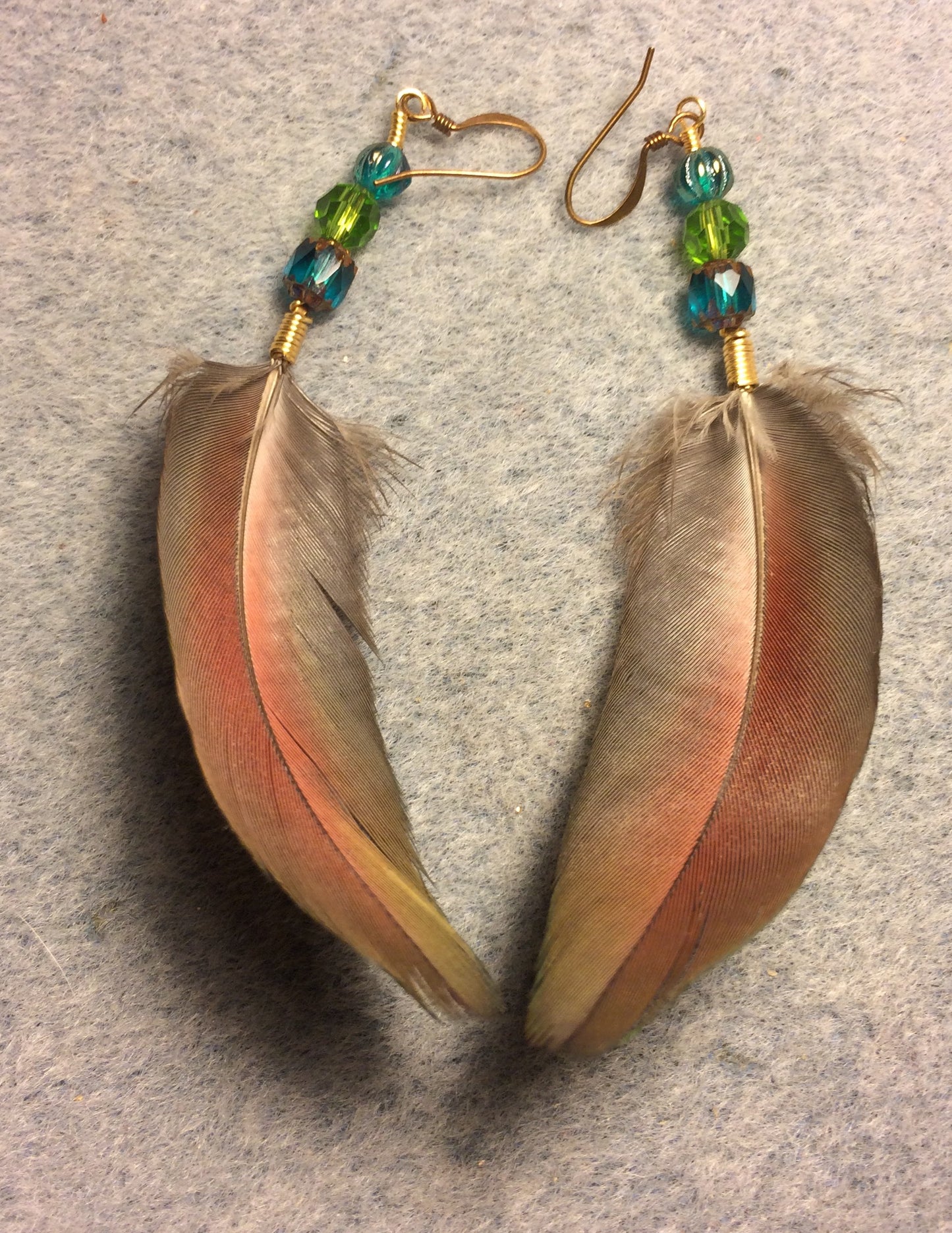 Green and blue greenwinged macaw feather earrings adorned with green and turquoise Czech glass beads.