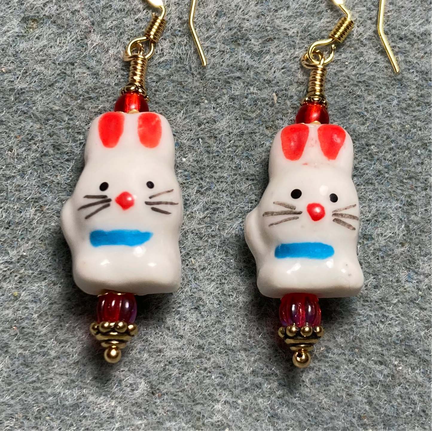 White, red, and blue ceramic rabbit bead earrings adorned with red Czech glass beads.