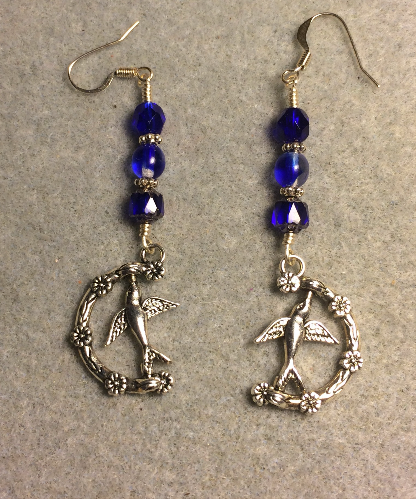 Silver spinning bird charm earrings adorned with dark blue Czech glass beads