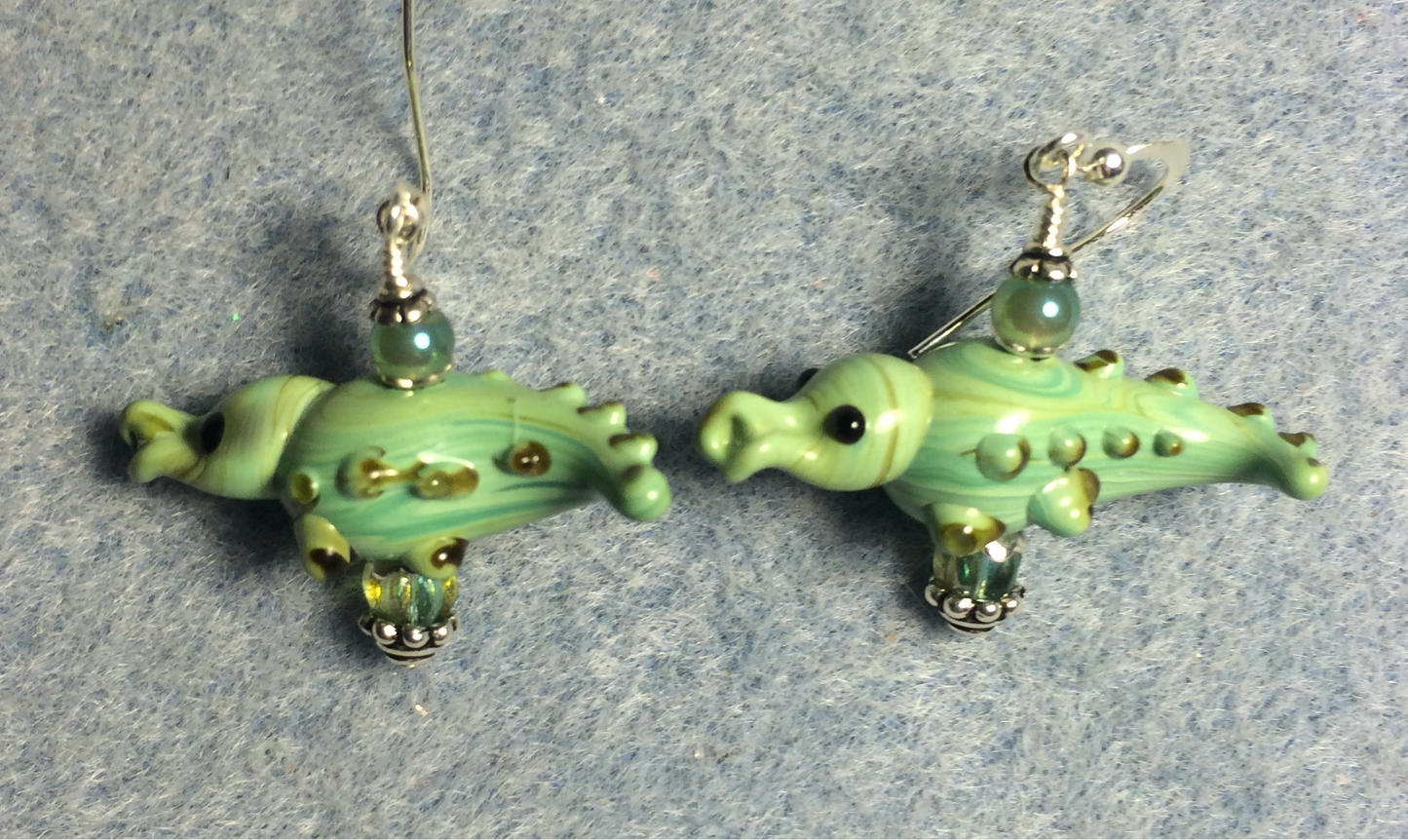 Opaque green lamp work spotted alligator bead earrings adorned with green Czech glass beads.