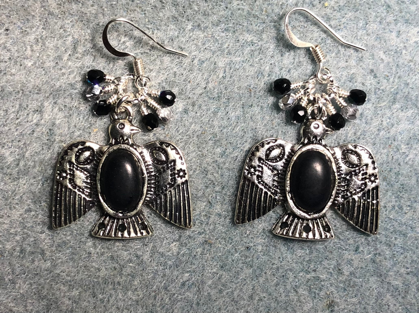 Silver and black onyx gemstone eagle charm earrings adorned with tiny dangling black and silver beads.