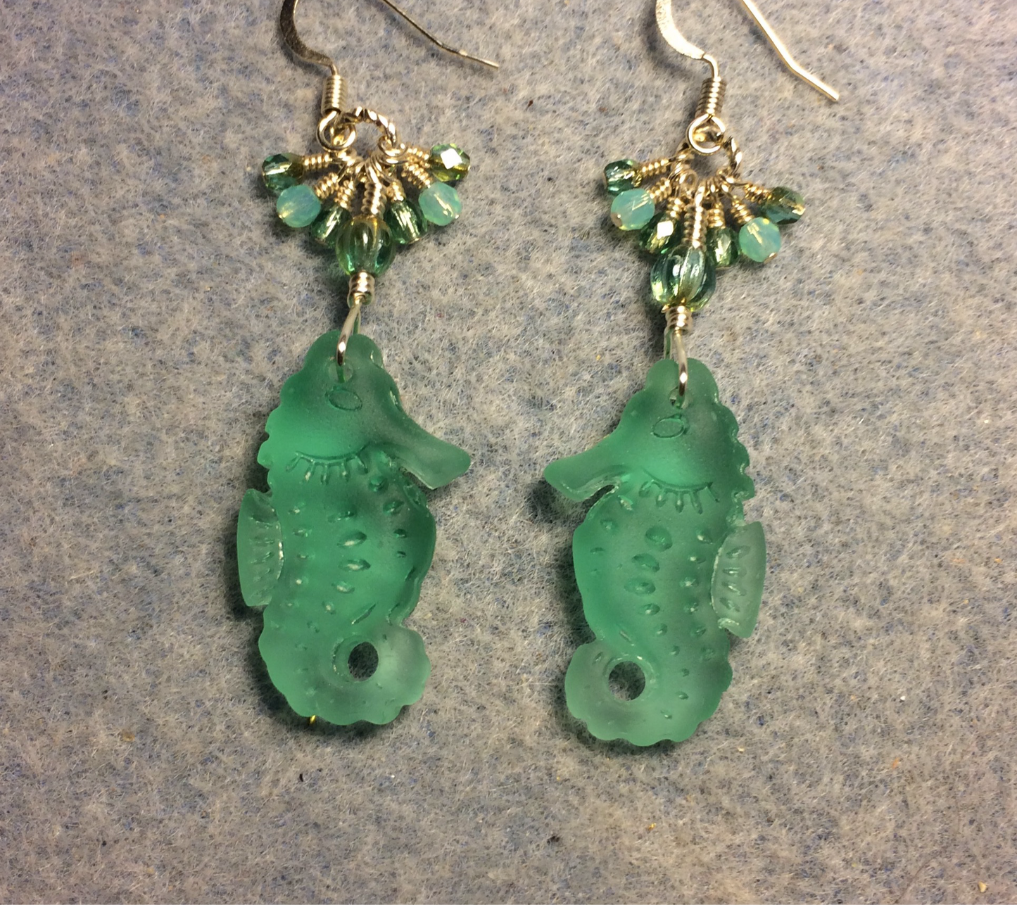 Blue green sea glass seahorse pendant bead earrings adorned with blue green Czech glass beads and small dangling blue green Czech glass beads.