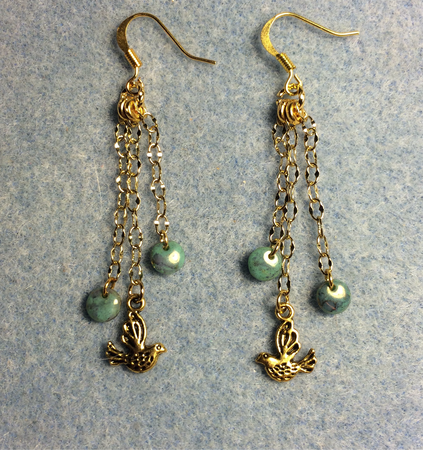 Small gold dove charm earrings attached to gold chain and adorned with small teal Czech glass lentil beads
