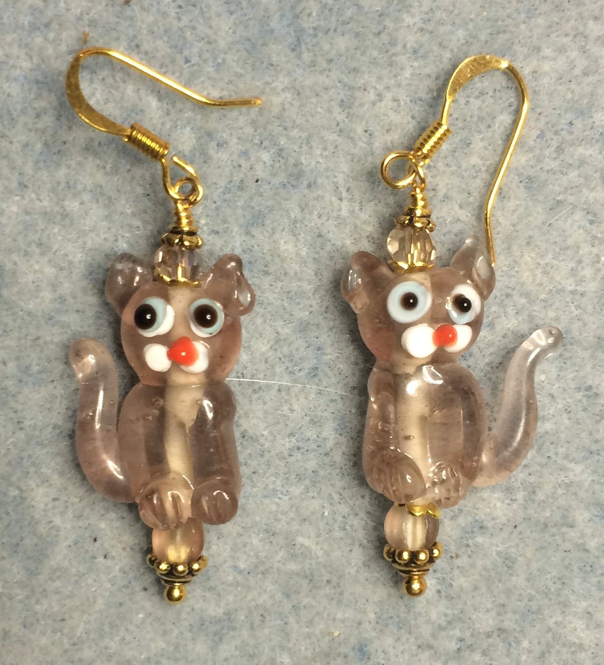 Translucent tan lamp work cat bead earrings adorned with tan Czech glass beads.