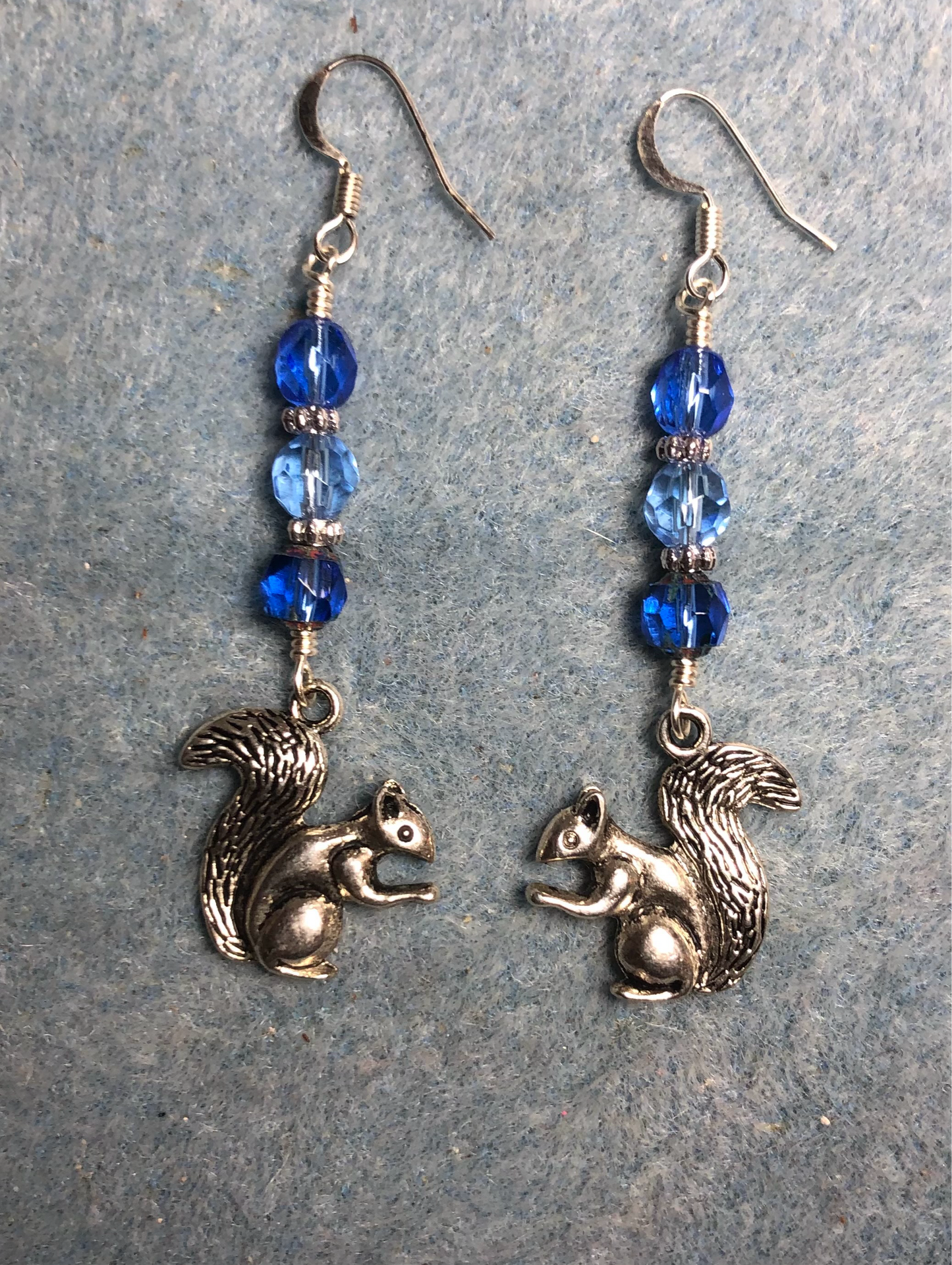 Silver squirrel charm earrings adorned with blue Czech glass melon beads.