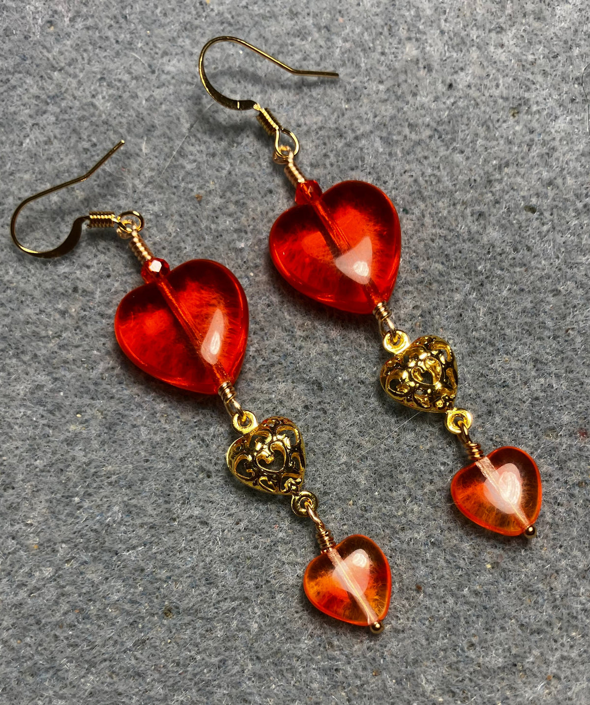 Large and small matching orange Czech glass heart bead earrings joined by gold filigree heart connectors.