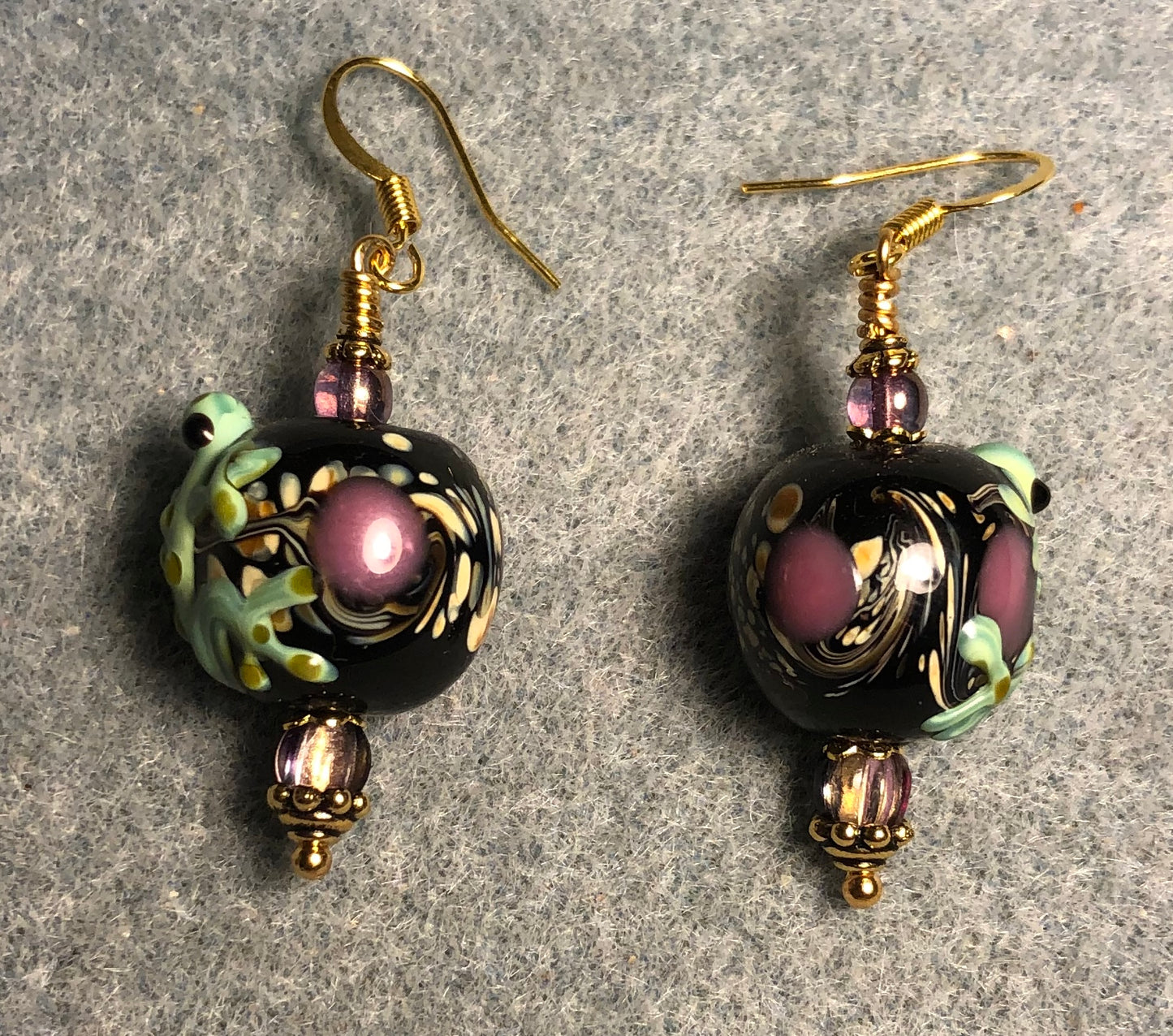 Green and purple lamp work frog bead earrings adorned with purple Czech glass beads.