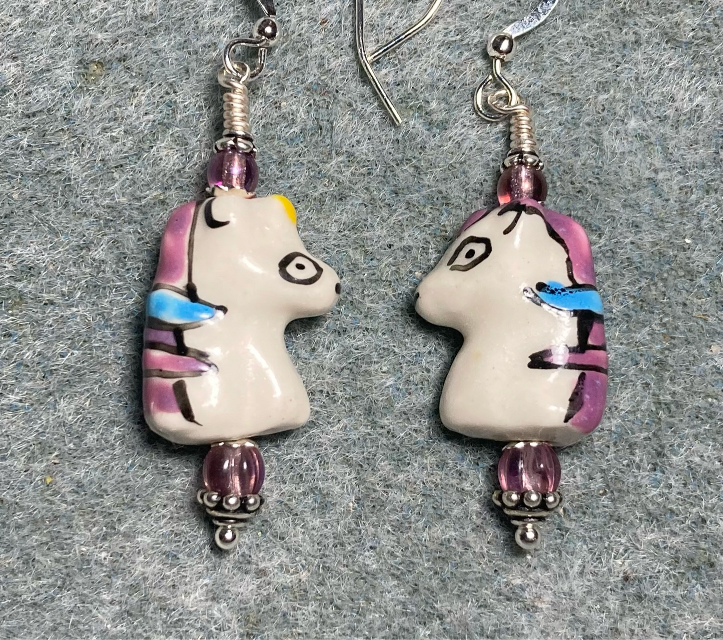 White, violet, and blue ceramic unicorn bead earrings adorned with violet Czech glass beads.