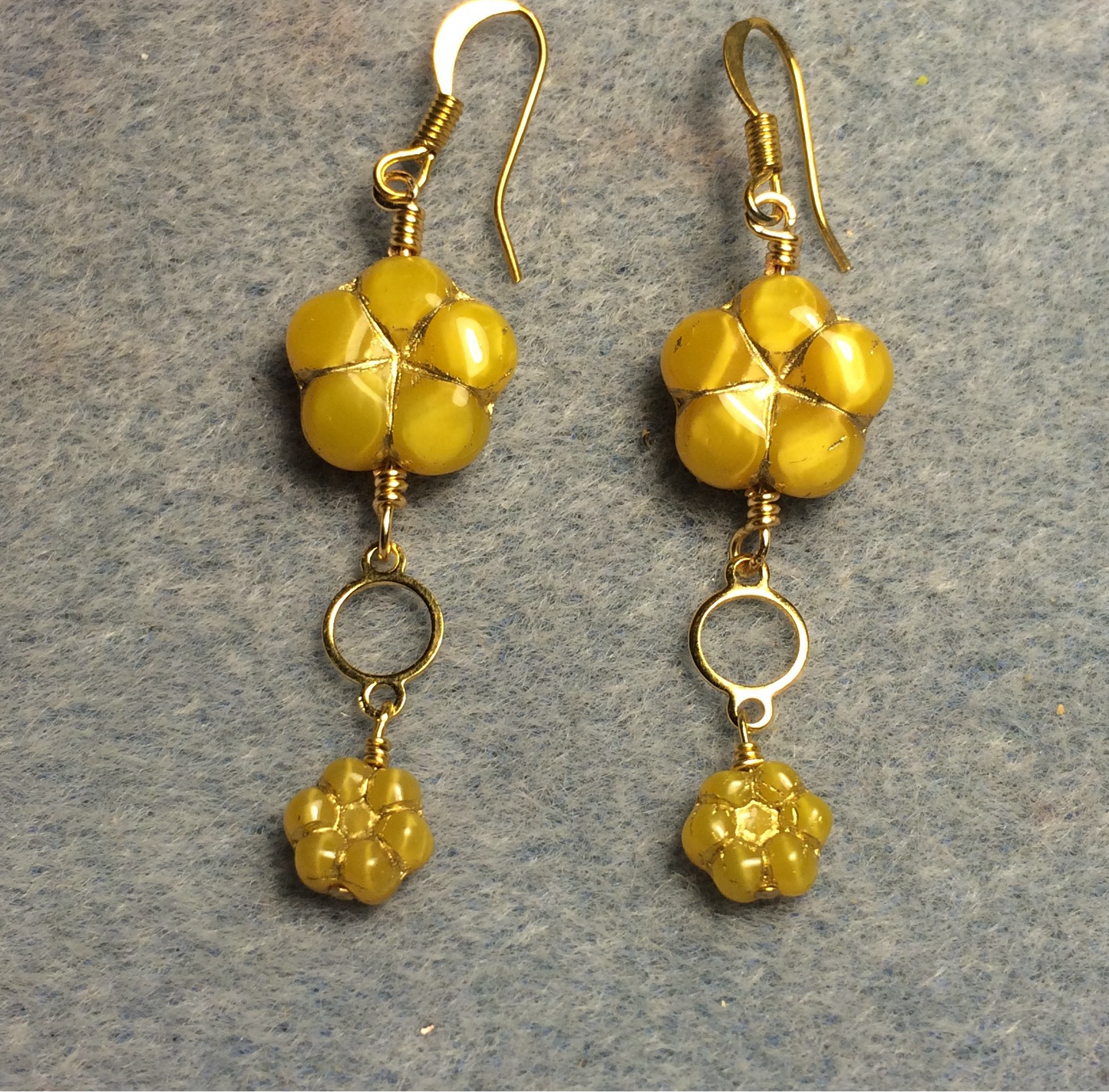 Golden yellow Czech glass puffy flower bead earrings adorned with gold circle connectors and small golden yellow Czech glass poppy beads.