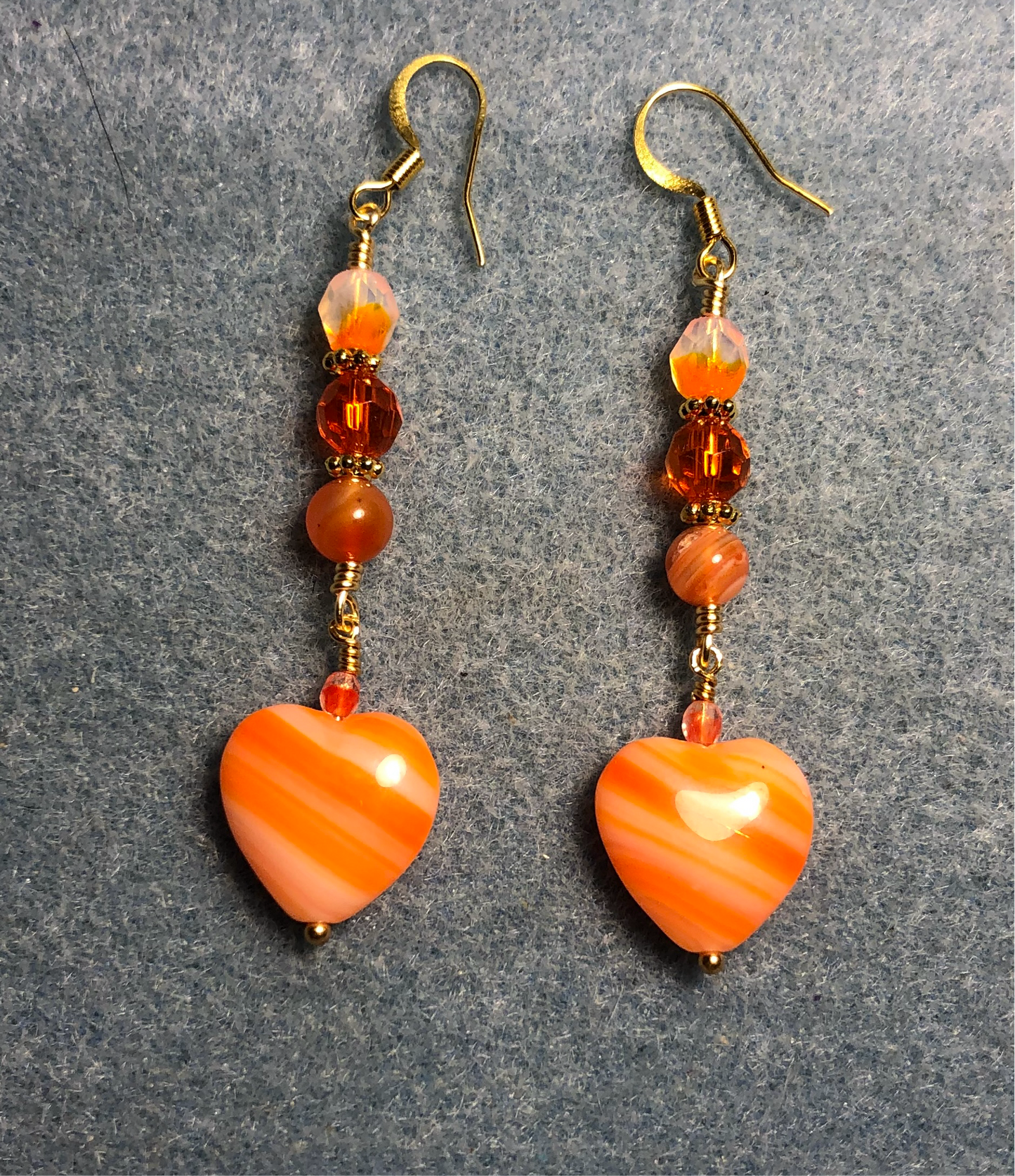 Opaque striped orange Czech glass heart bead earrings adorned with orange Czech glass beads.