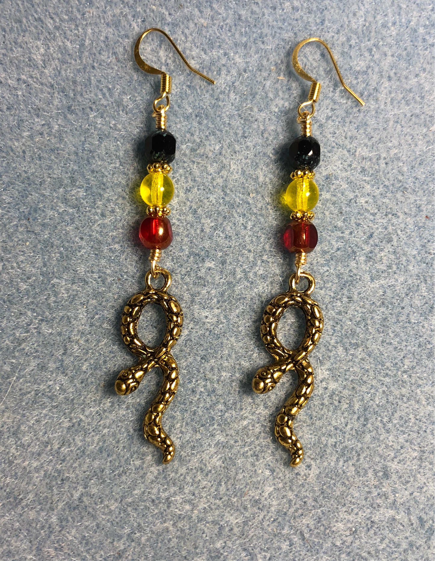 Gold snake charm earrings adorned with red, yellow, and black Czech glass beads