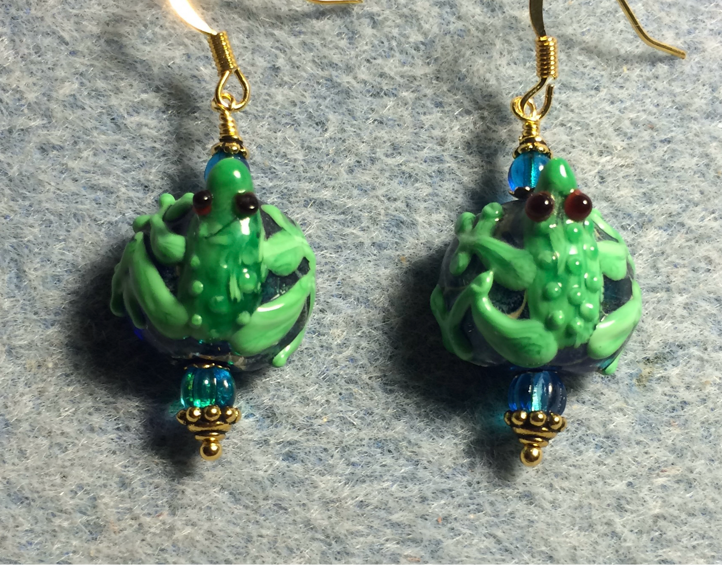 Turquoise and green lamp work frog bead earrings adorned with turquoise Czech glass beads.