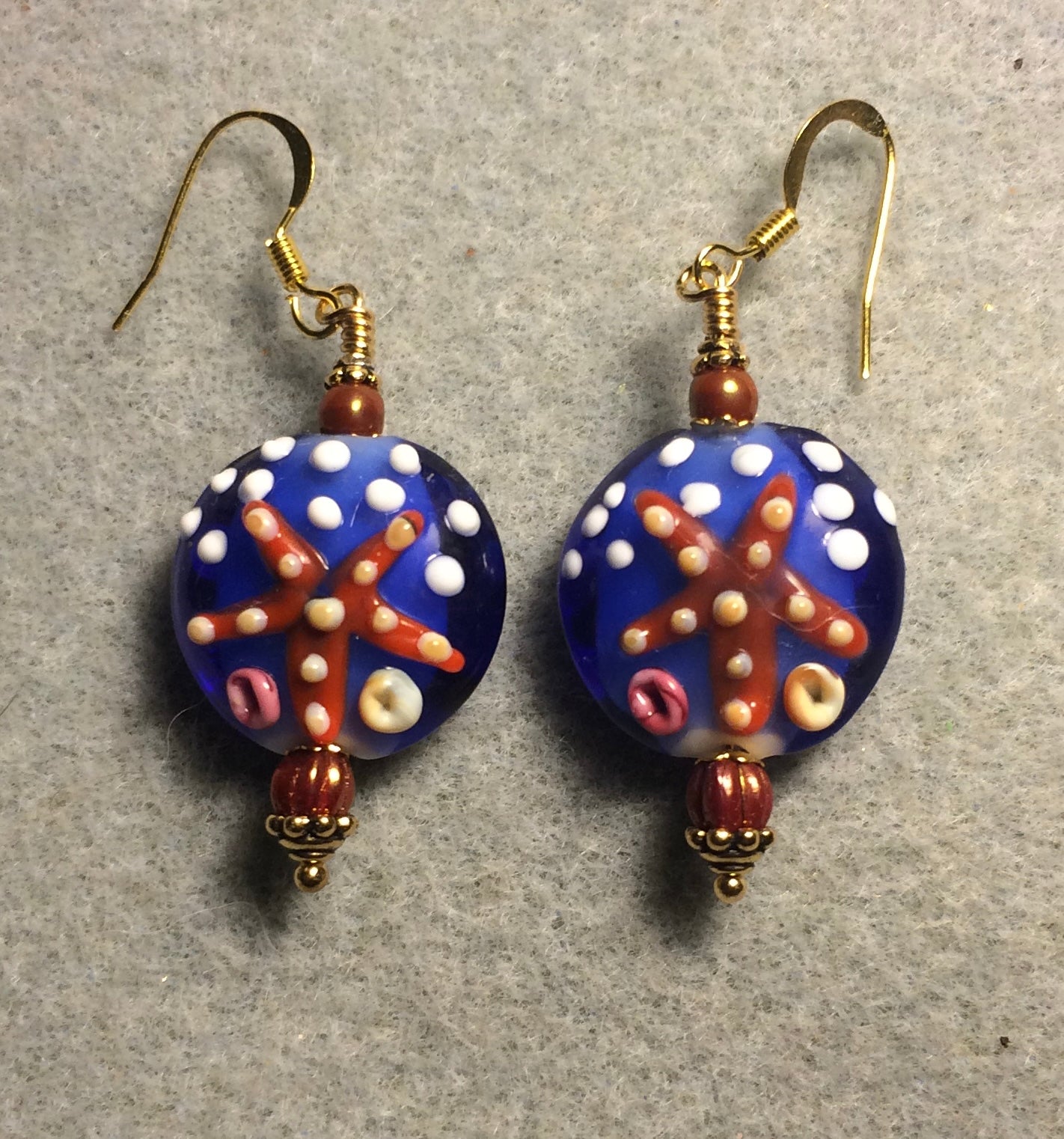 Blue and orange polka dotted lamp work starfish bead earrings adorned with dark orange Chinese crystal beads.
