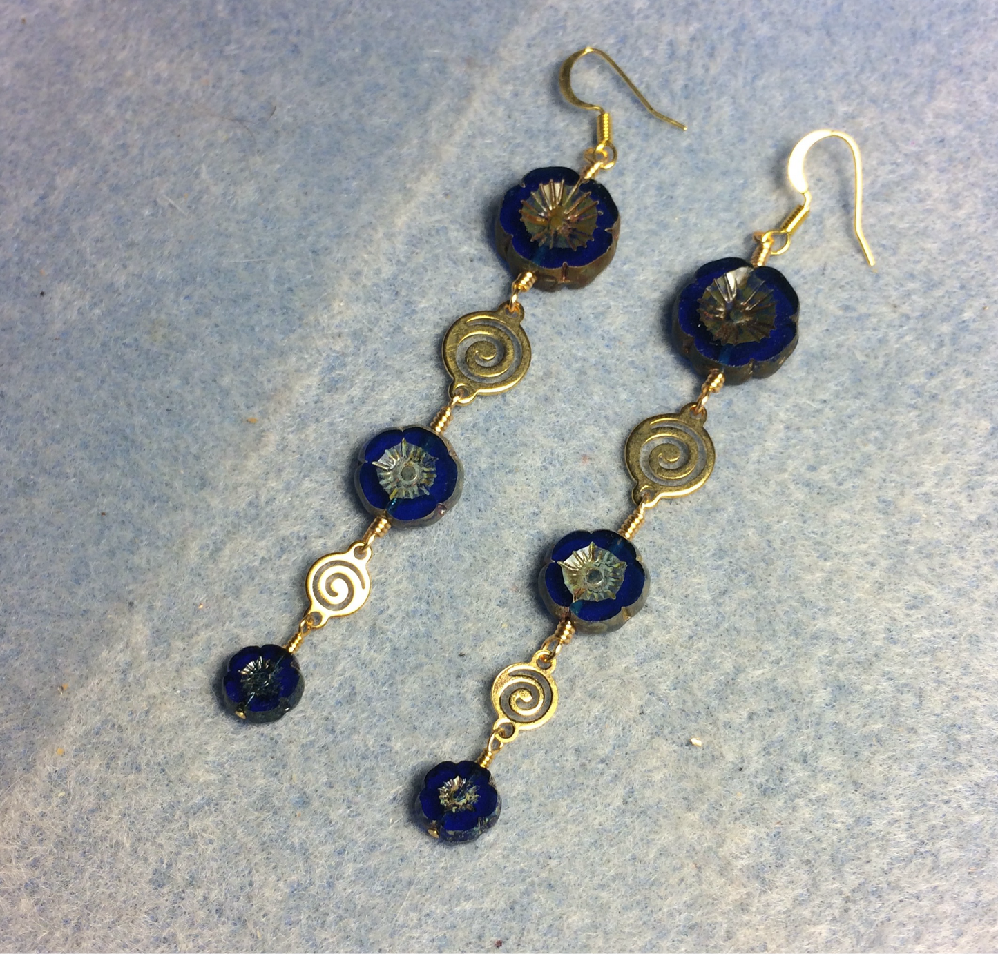 Extra long blue flower bead earrings made with three sizes of cobalt blue Czech glass pansy beads joined by gold swirly connectors.