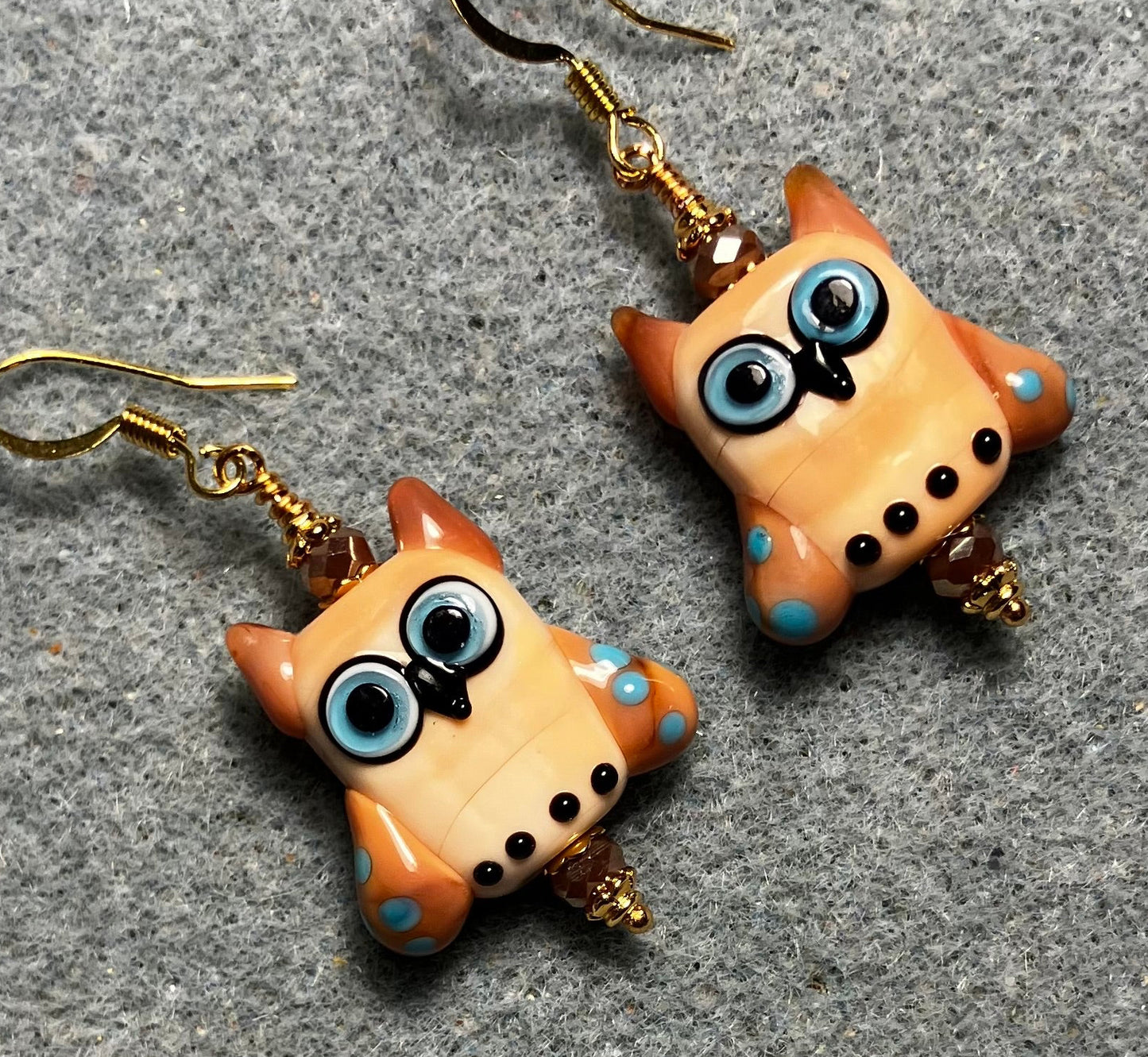 Beige, caramel, and blue lamp work owl bead earrings adorned with beige Chinese crystal beads.