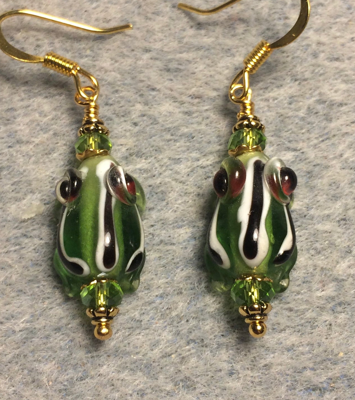 Very small translucent olive green with black and white stripes lamp work frog bead earrings adorned with olive green Chinese crystal beads.
