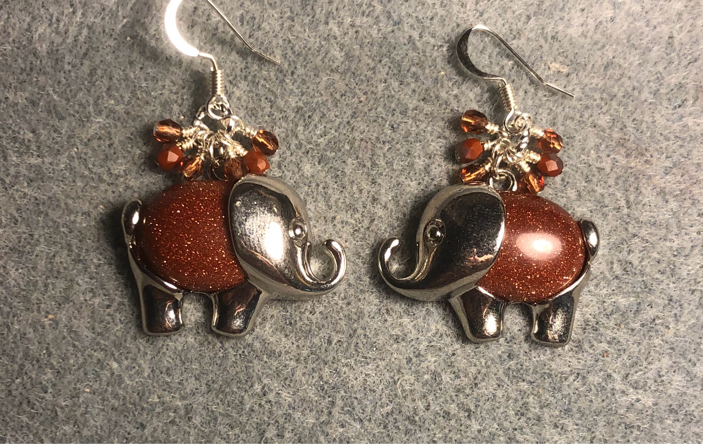 Large silver and orange goldstone gemstone elephant charm earrings adorned with small dangling orange Czech glass beads.