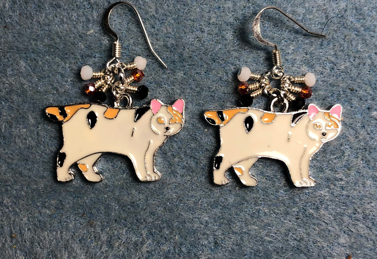 White, orange, and black enamel calico Manx cat charm earrings adorned with tiny dangling white, orange, and black Chinese crystal beads.