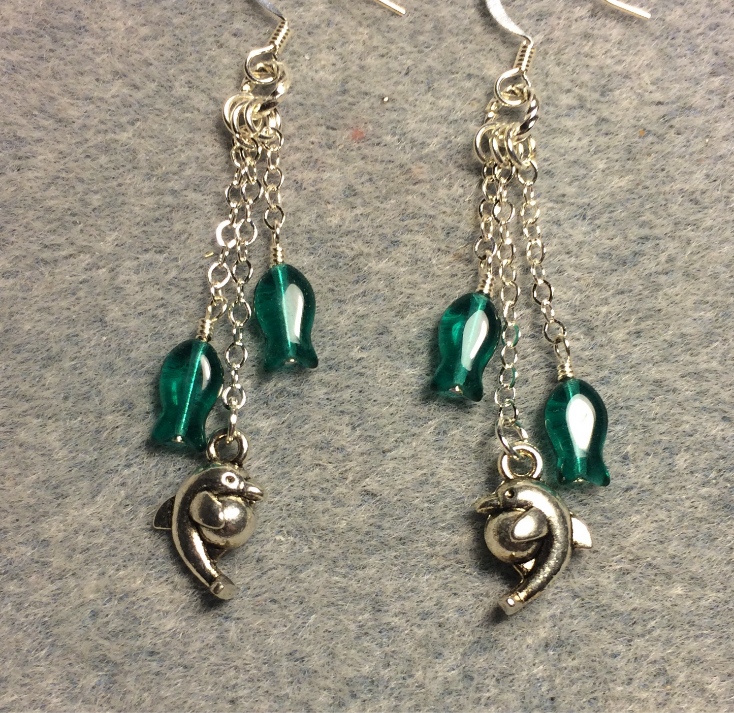 Small silver dolphin charm earrings attached to silver chain and adorned with small teal Czech glass fish beads