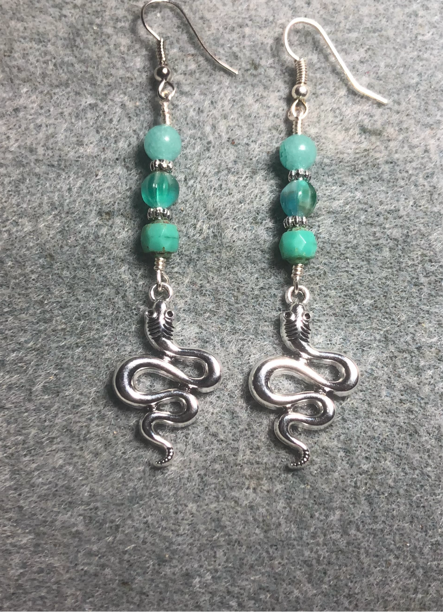 Silver coiled snake charm earrings adorned with milky turquoise Czech glass beads.