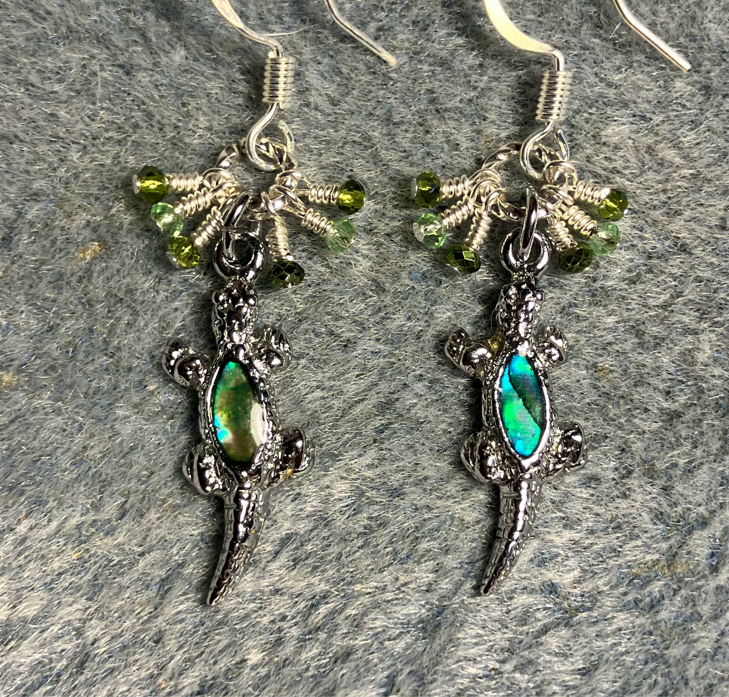 Small silver and abalone lizard charm earrings adorned with tiny dangling green Chinese crystal beads.
