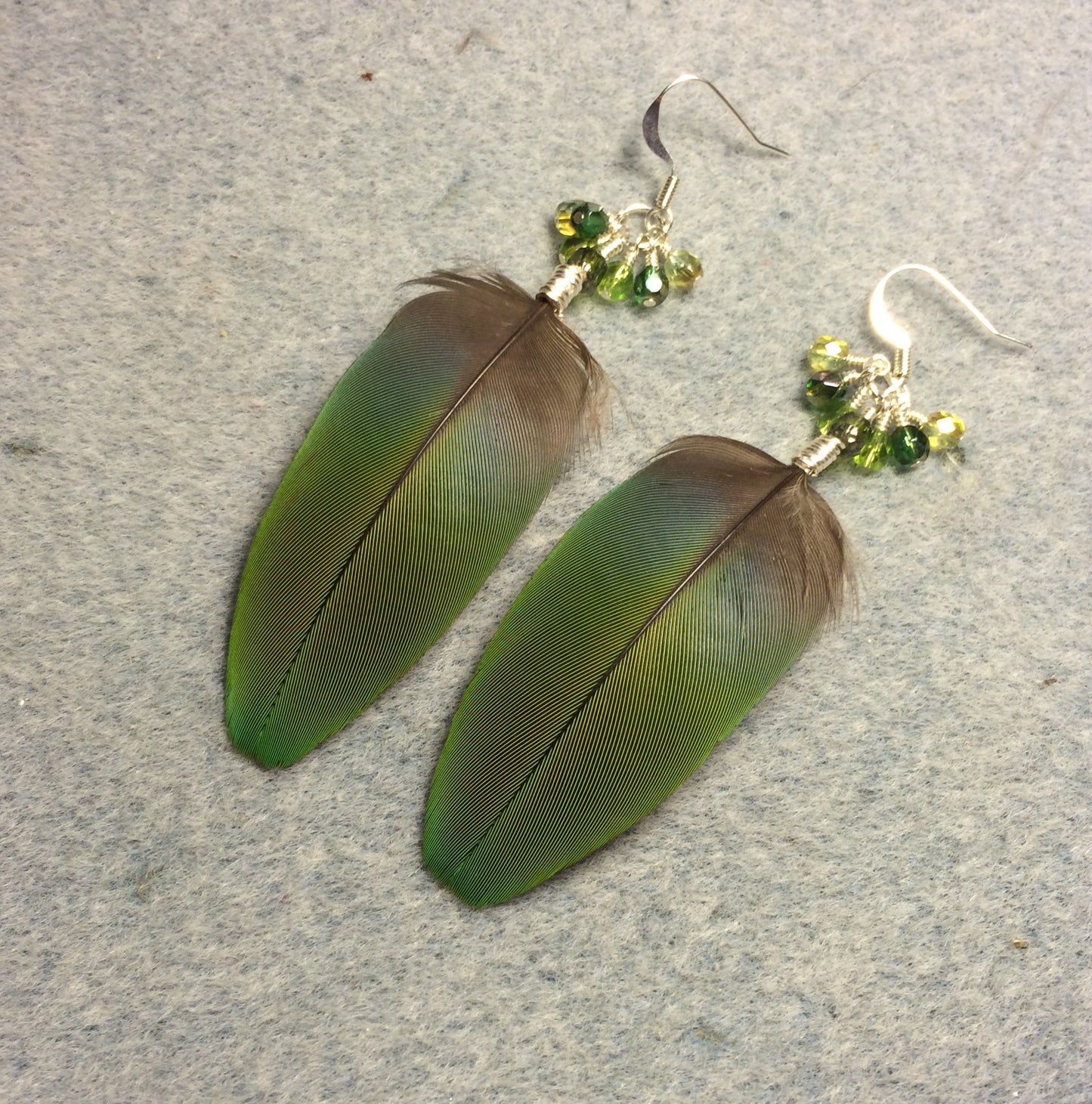 Blue green macaw feather earrings adorned with small dangling green Czech glass beads