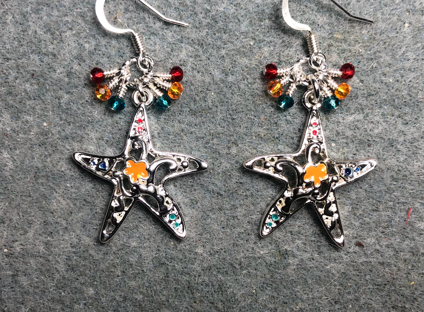 Silver and orange enamel starfish charm earrings adorned with tiny dangling turquoise, orange, and red Chinese crystal beads.