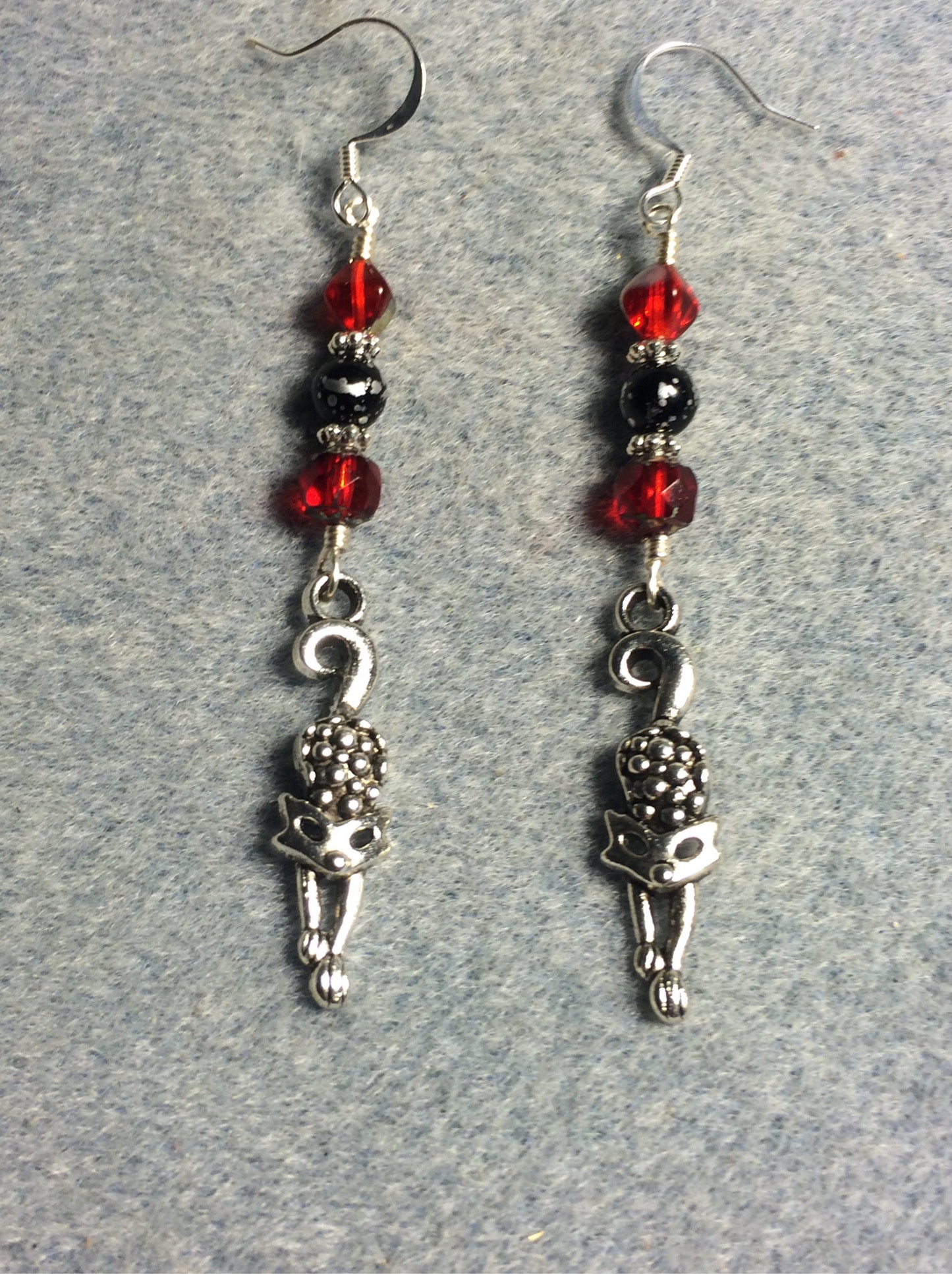 Silver stretching cat charm earrings adorned with red and black Czech glass melon beads.