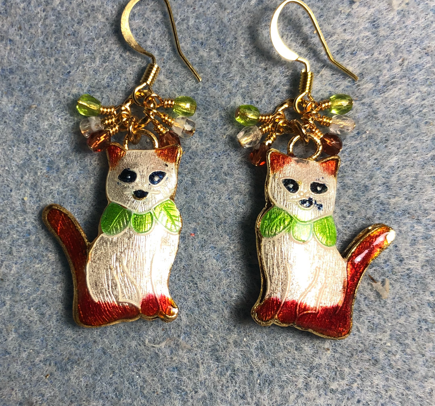 White, olive green, and rose cloisonné cat charm earrings adorned with small dangling clear, olive green, and rose Czech glass beads.