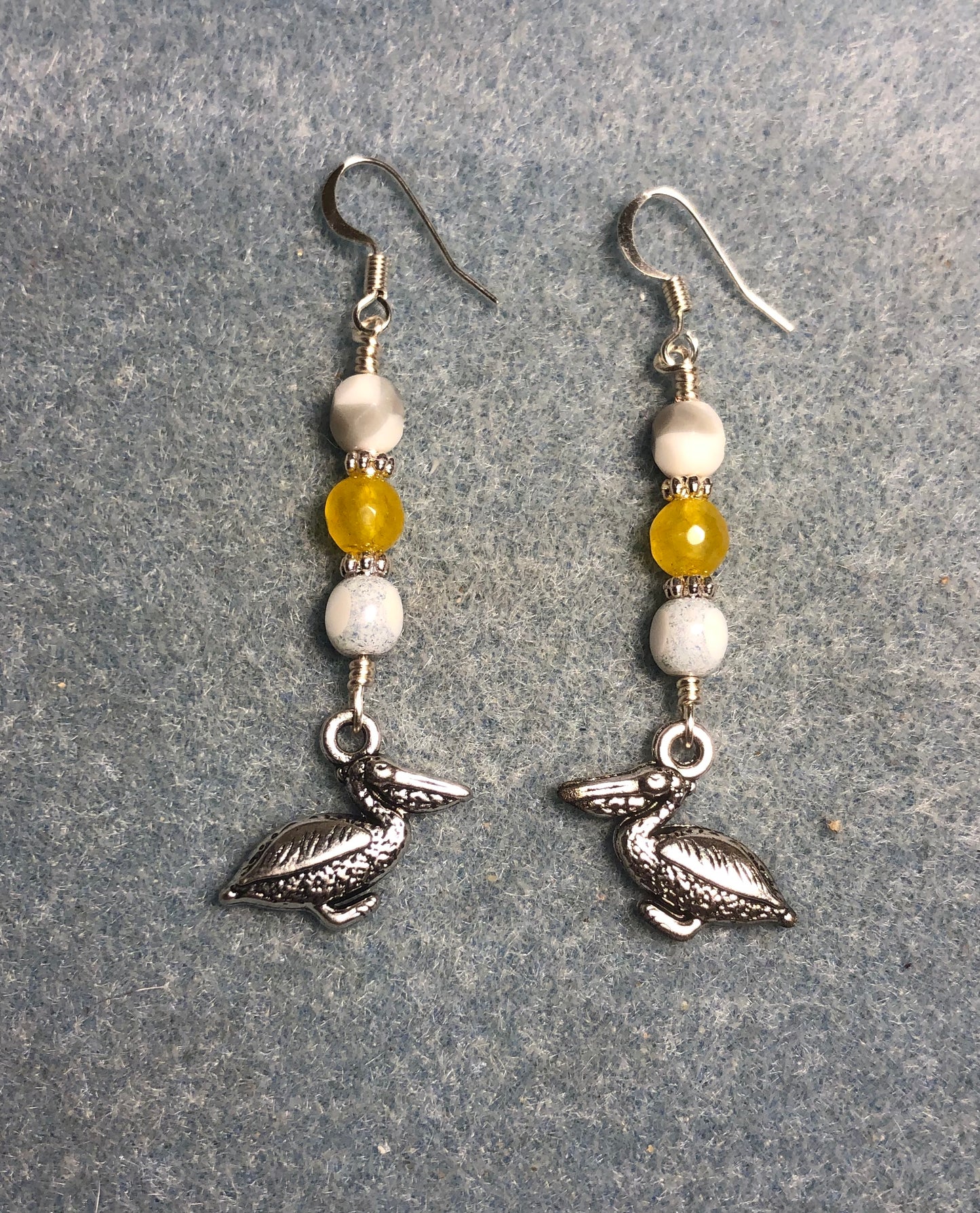 Silver pelican charm earrings adorned with white and amber Czech glass beads