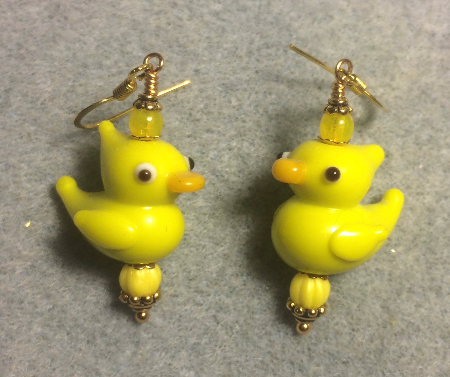 Yellow lamp work duck bead earrings adorned with yellow Czech glass beads.
