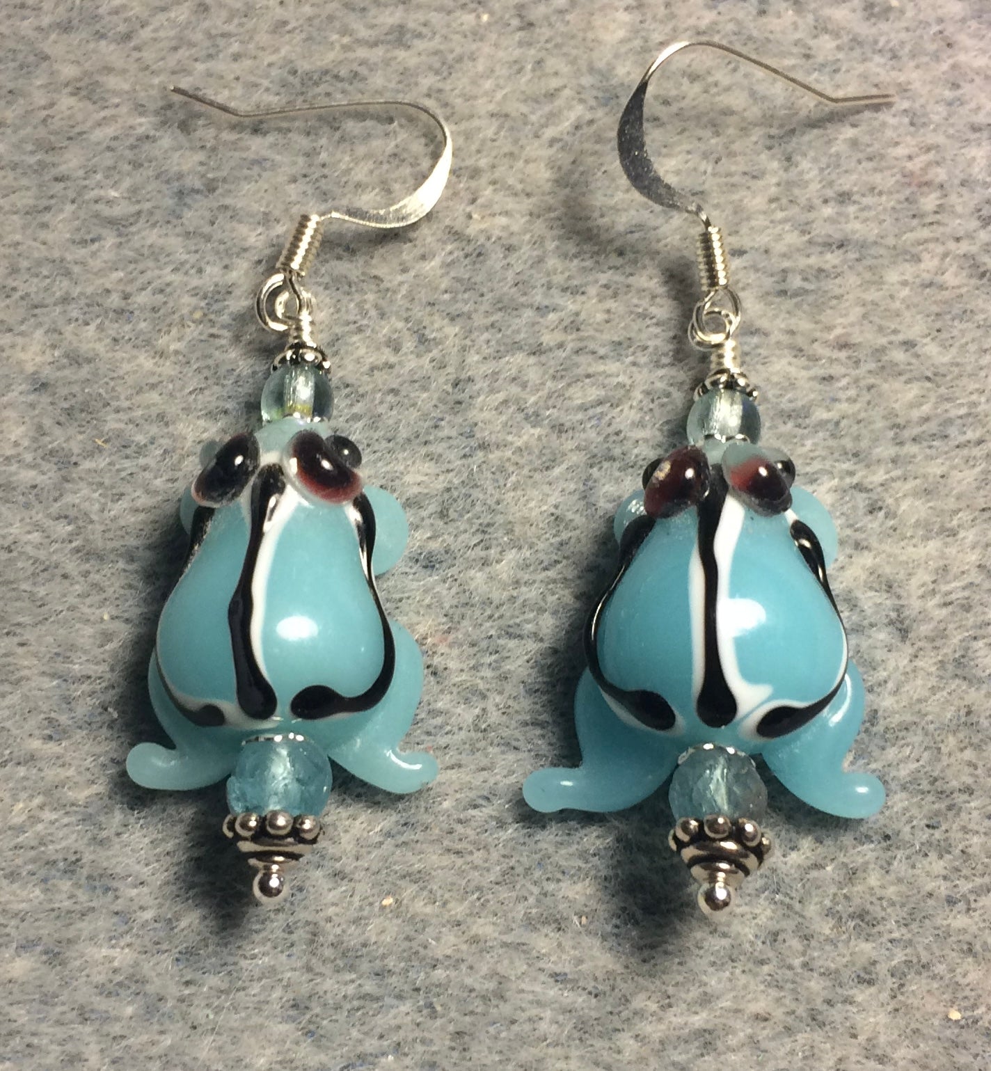 Opaque light turquoise lamp work striped frog bead earrings adorned with light turquoise Czech glass beads.