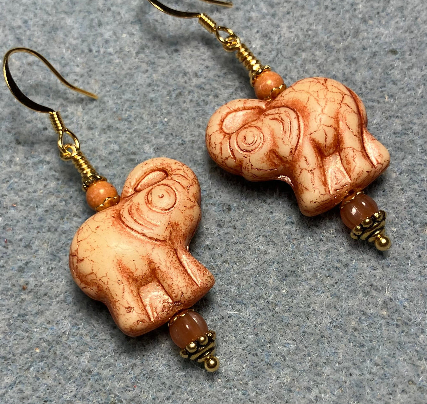 Light beige (with orange inlay) Czech glass elephant bead earrings adorned with orange Czech glass beads.