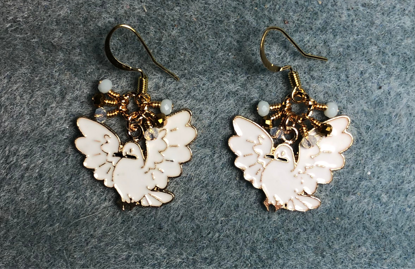 White and gold enamel flying dove charm earrings adorned with tiny dangling white, gold, and clear Chinese crystal beads.