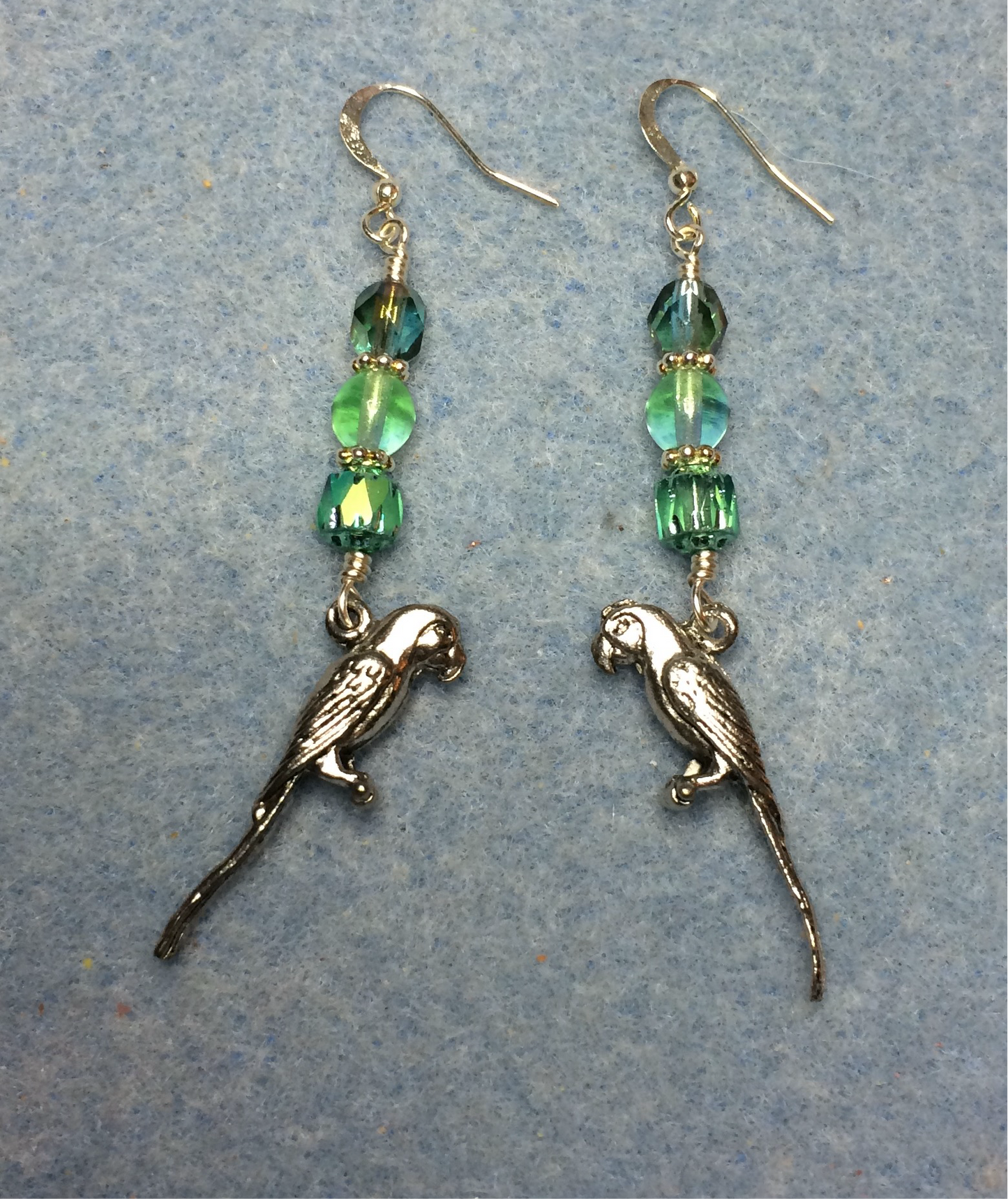 Silver parrot charm earrings adorned with light green Czech glass beads