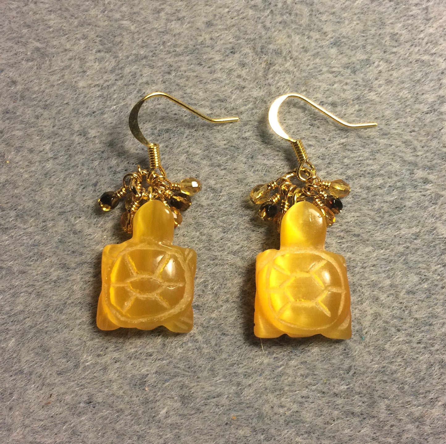 Carved amber fiber optic (cat’s eye) turtle bead earrings adorned with small dangling amber and topaz Czech glass beads.