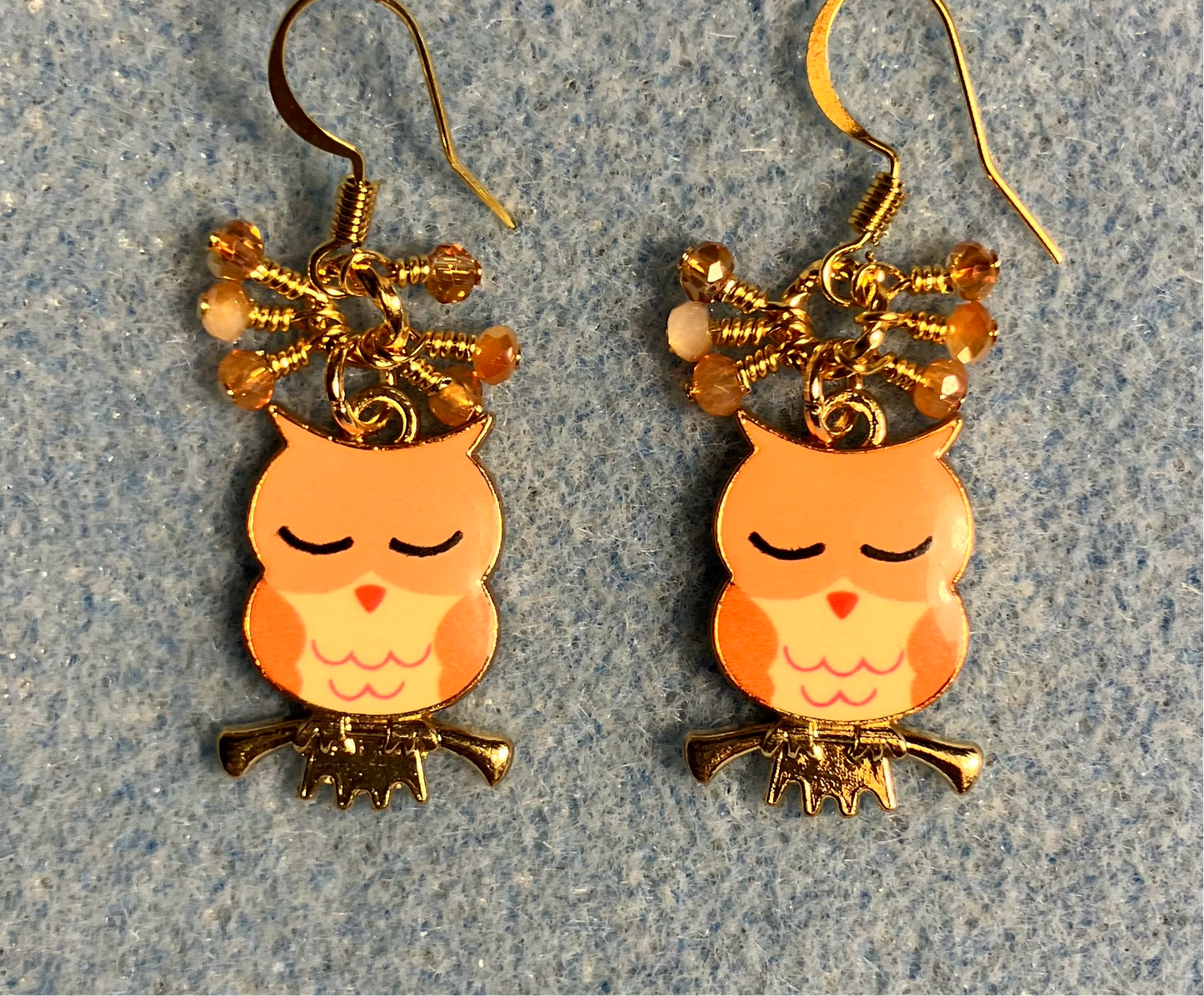 Orange, amber, and peach enamel sleepy owl charm earrings adorned with tiny dangling orange, amber, and peach Chinese crystal beads.