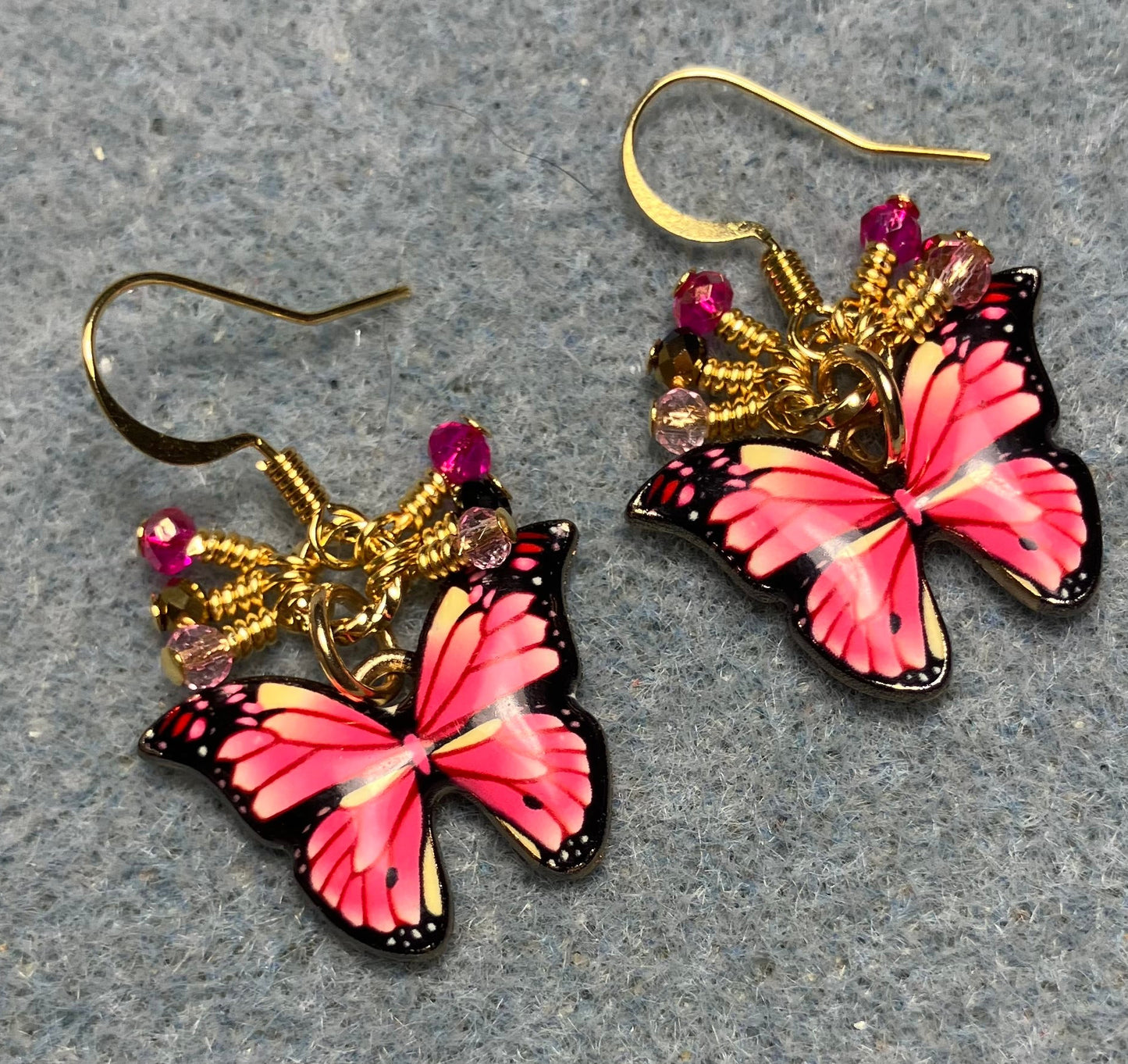 Hot pink and light pink enamel butterfly charm earrings adorned with tiny dangling hot pink, gold, and light pink Chinese crystal beads.