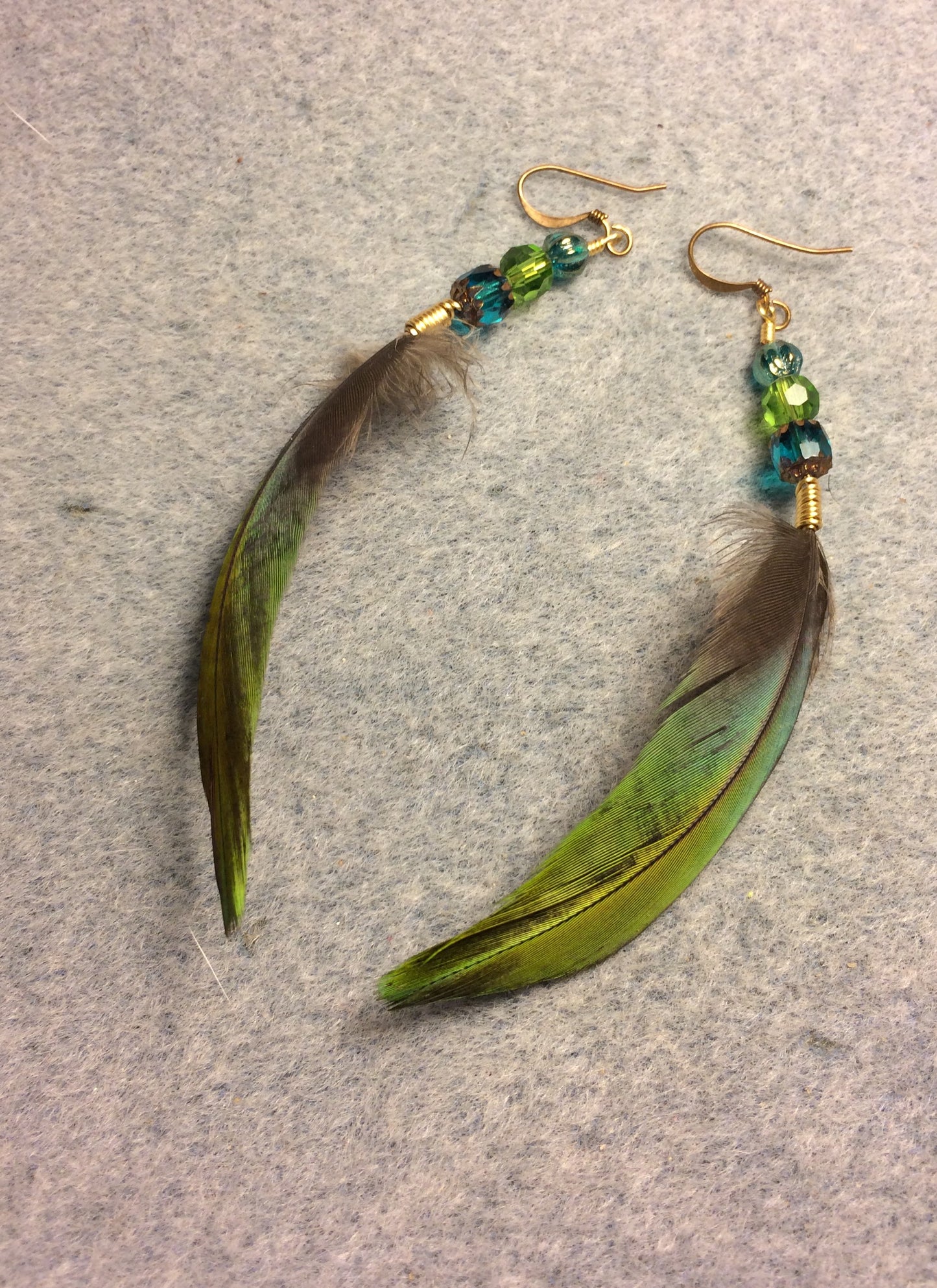 Green and blue greenwinged macaw feather earrings adorned with green and turquoise Czech glass beads.