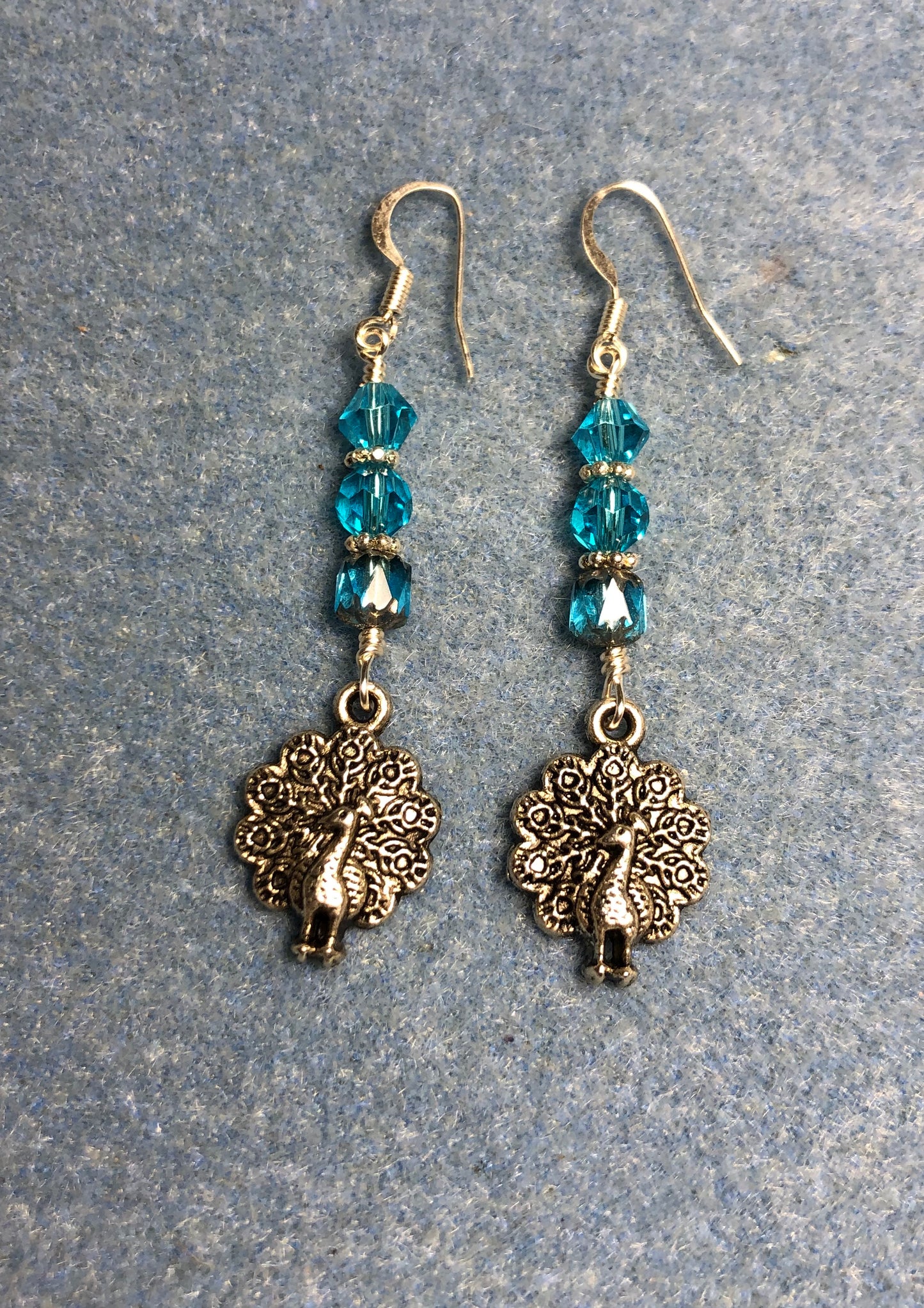 Silver peacock charm earrings adorned with turquoise Czech glass beads