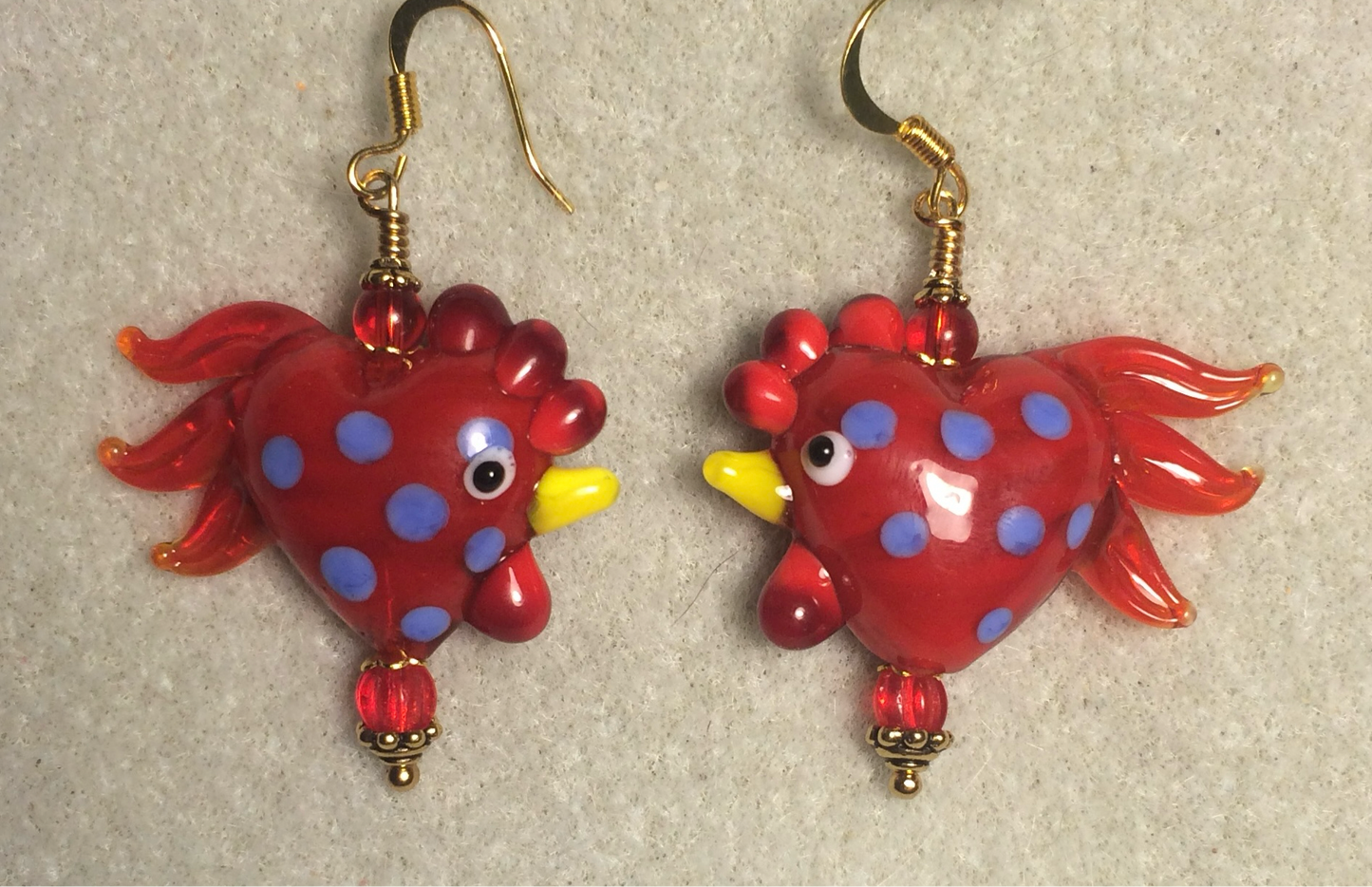 Red with blue spots heart shaped lamp work rooster bead earrings adorned with red Czech glass beads.