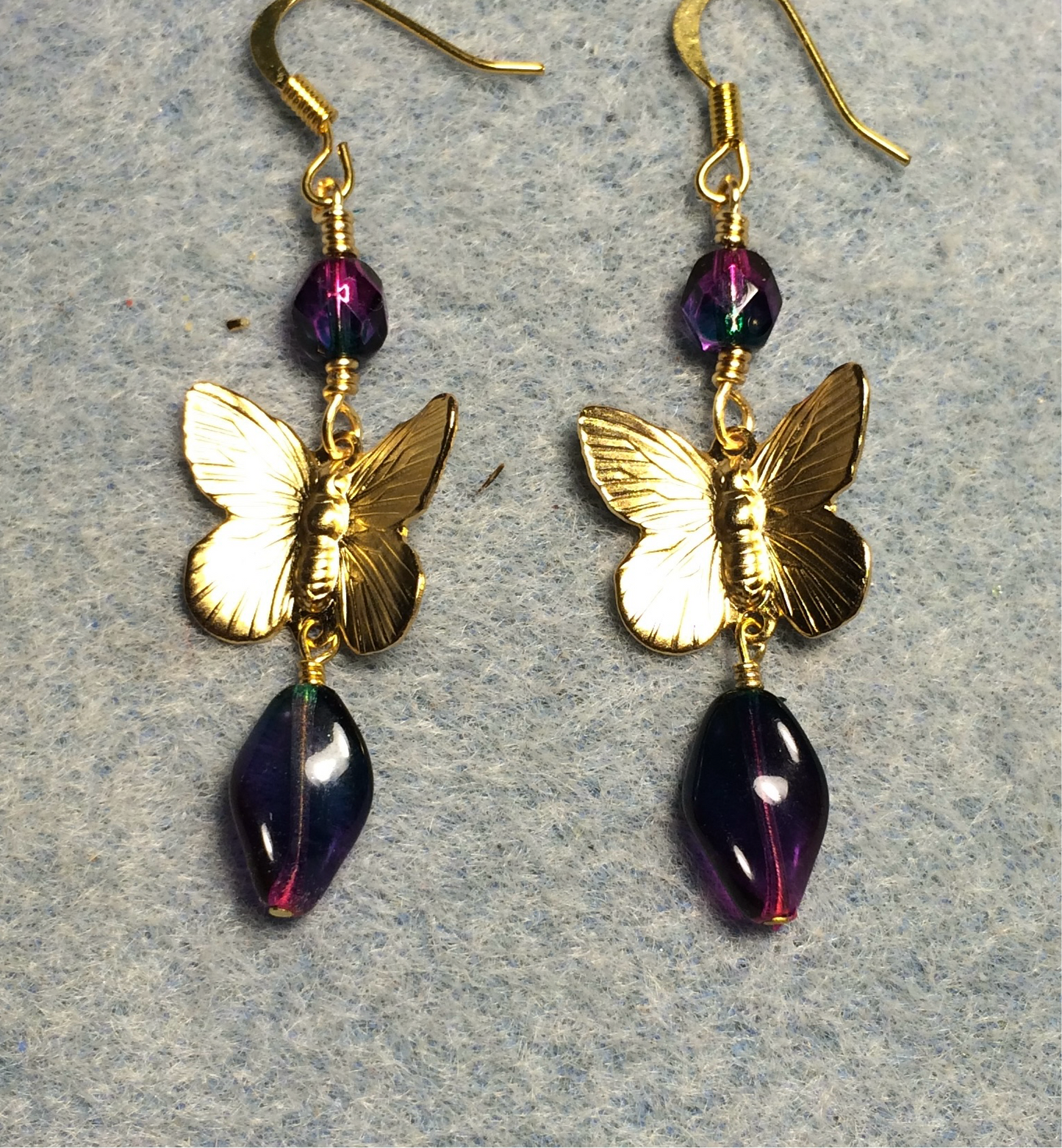 Gold butterfly charm connector earrings adorned with purple green Czech glass twist beads and purple green Czech glass beads.